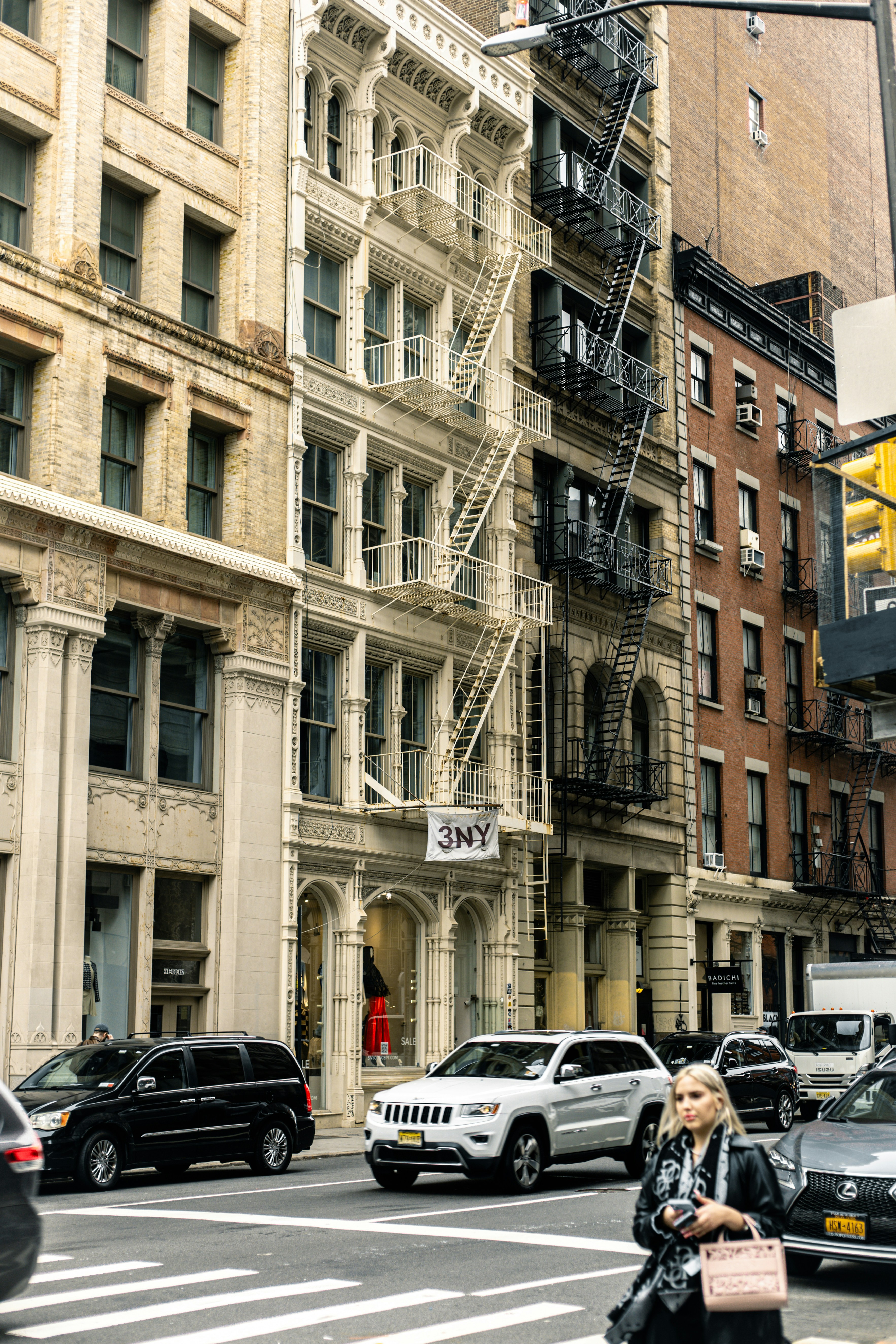A woman walking across a street next to tall buildings