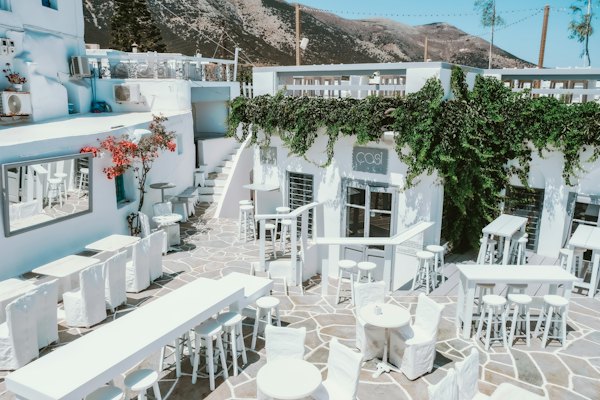 Tables and chairs outside of a restaurant with a mountain in the background — Sifnos, Greece