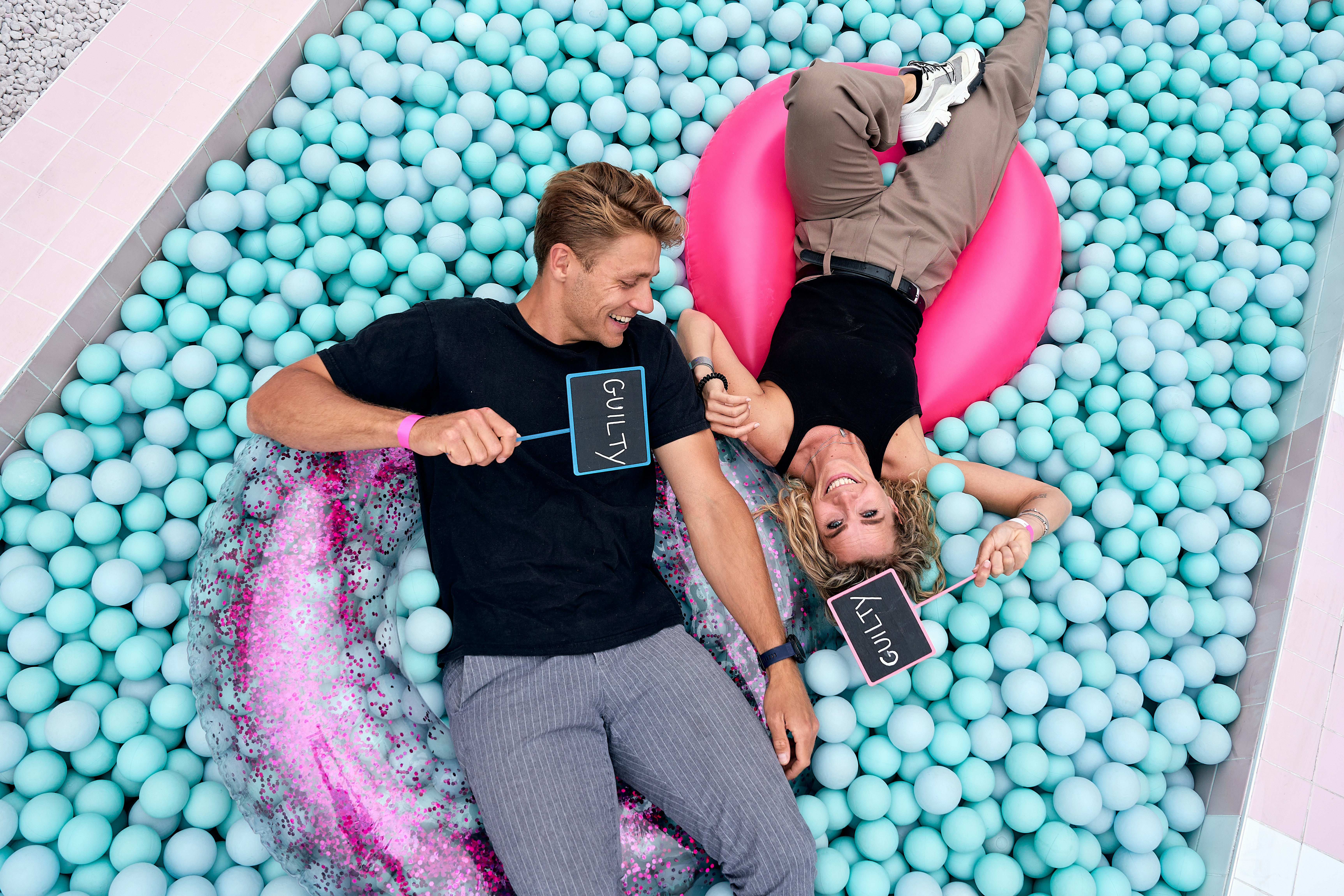 A man and a woman laying in a pool of balls
