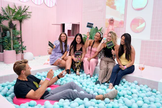 A group of people sitting in a bathtub filled with blue balls