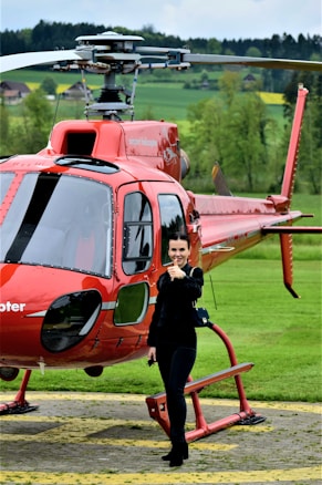 A woman standing in front of a red helicopter