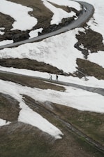 A couple of people walking down a snow covered road