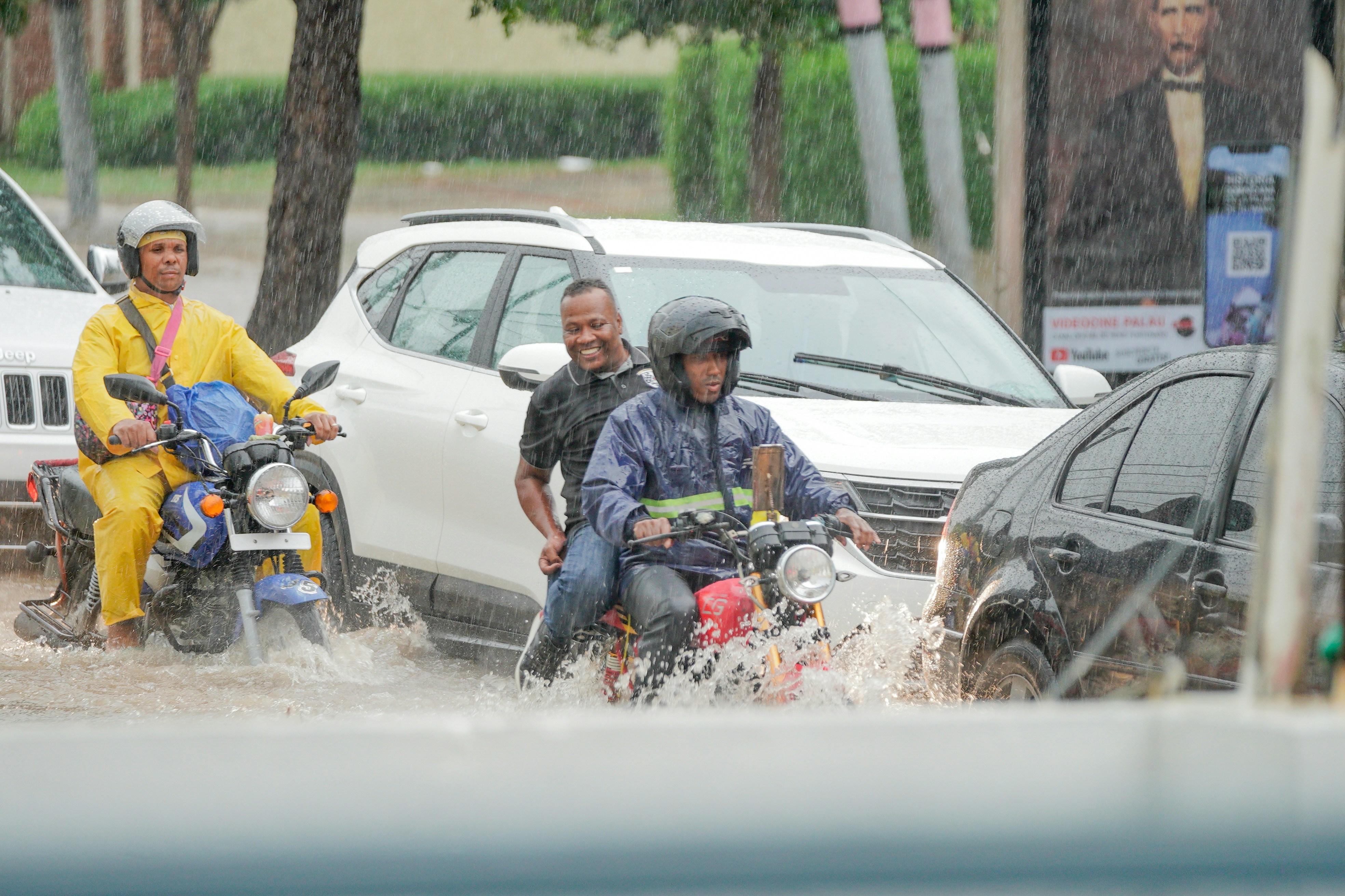 A group of people riding motorcycles through a flooded street