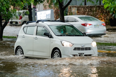 A white car driving through a flooded street