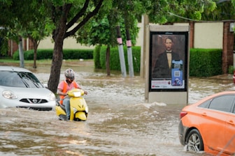 A couple of people on a motor scooter in a flooded street