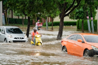 A group of people riding motorcycles through a flooded street