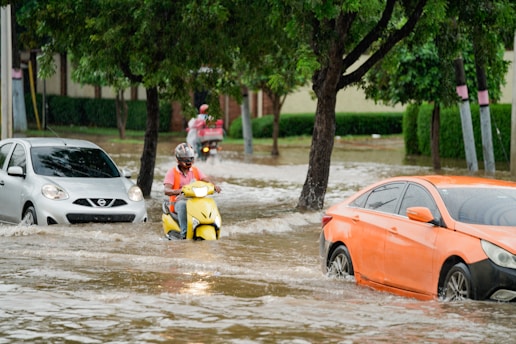 A group of people riding motorcycles through a flooded street