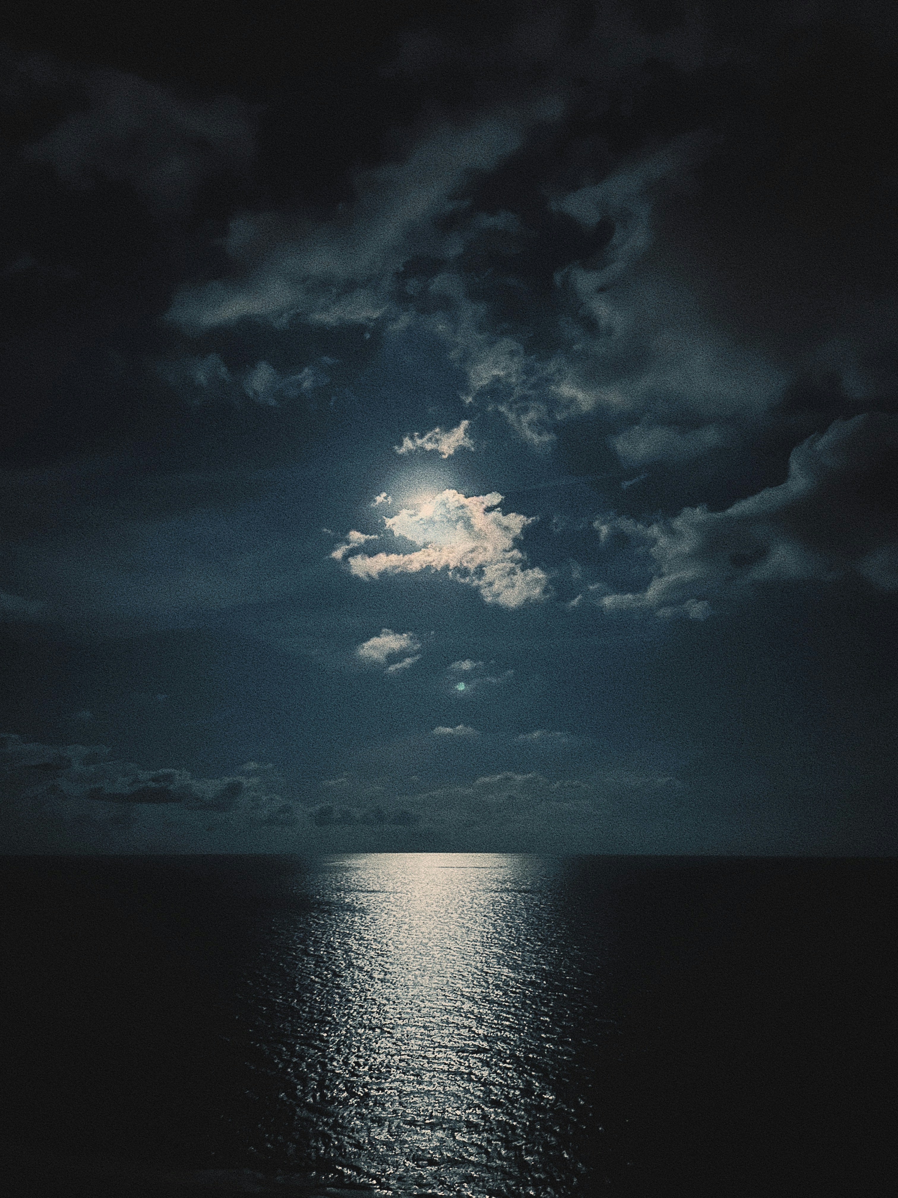 A full moon shines in the sky over the ocean