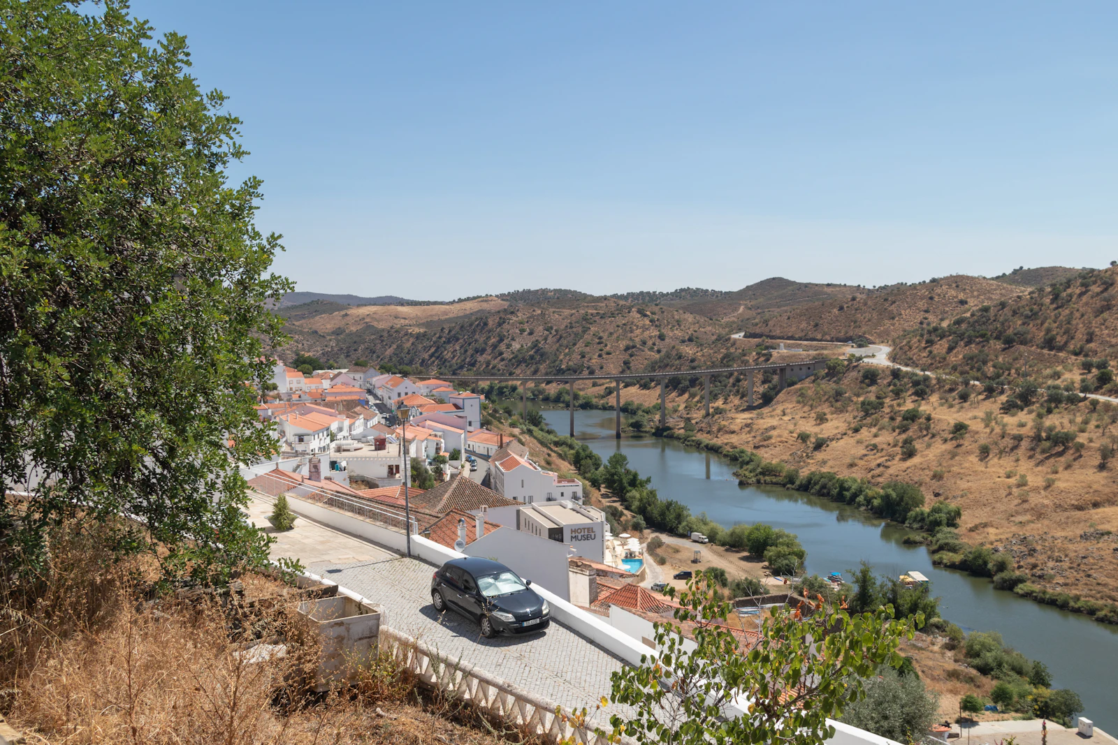 A car on a road beside a slow river.