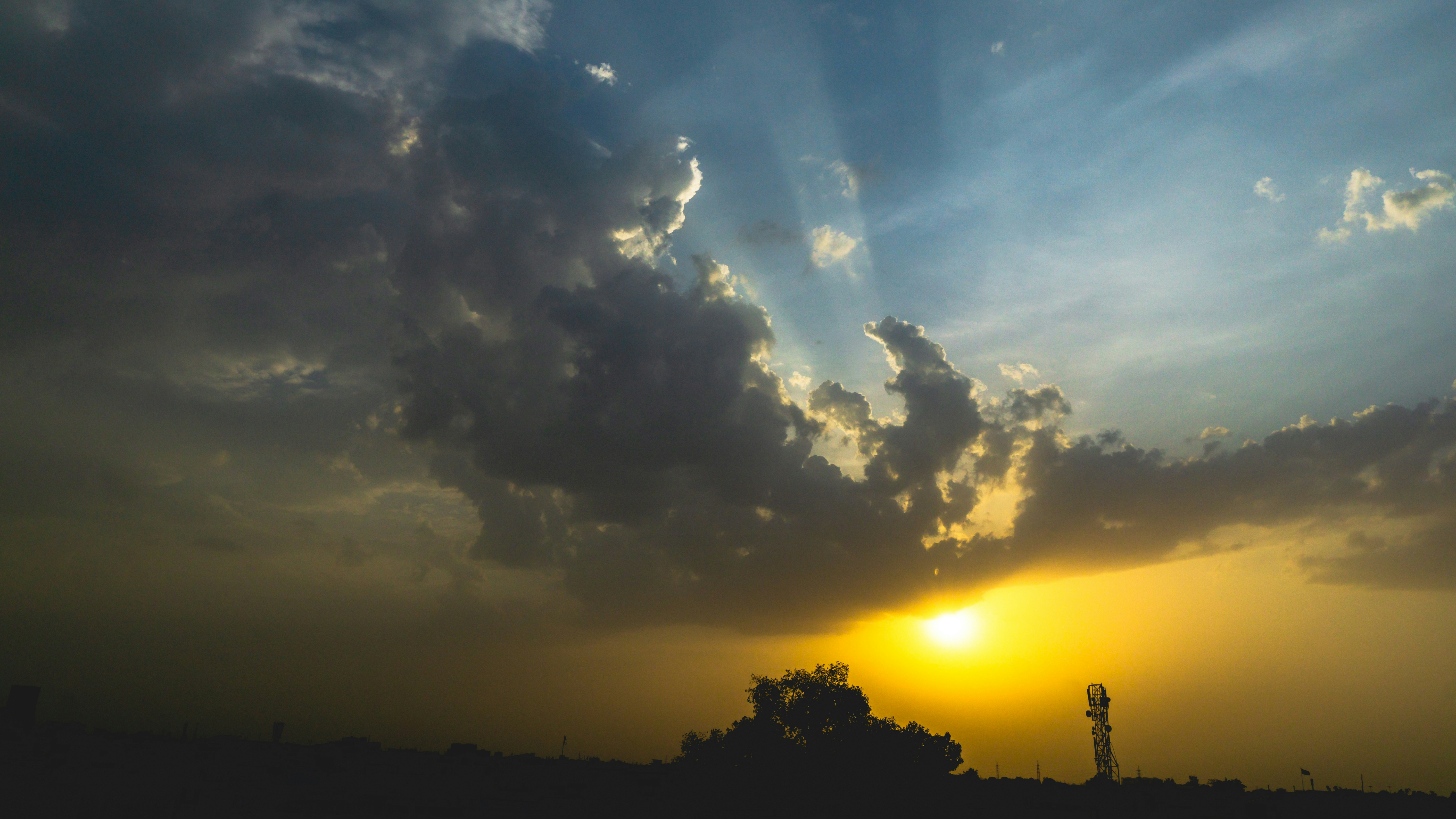 The sun is setting behind a cloud filled sky