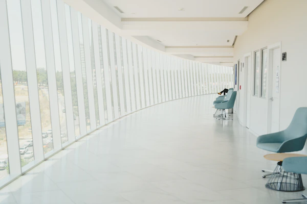 A long hallway with a row of chairs next to a wall