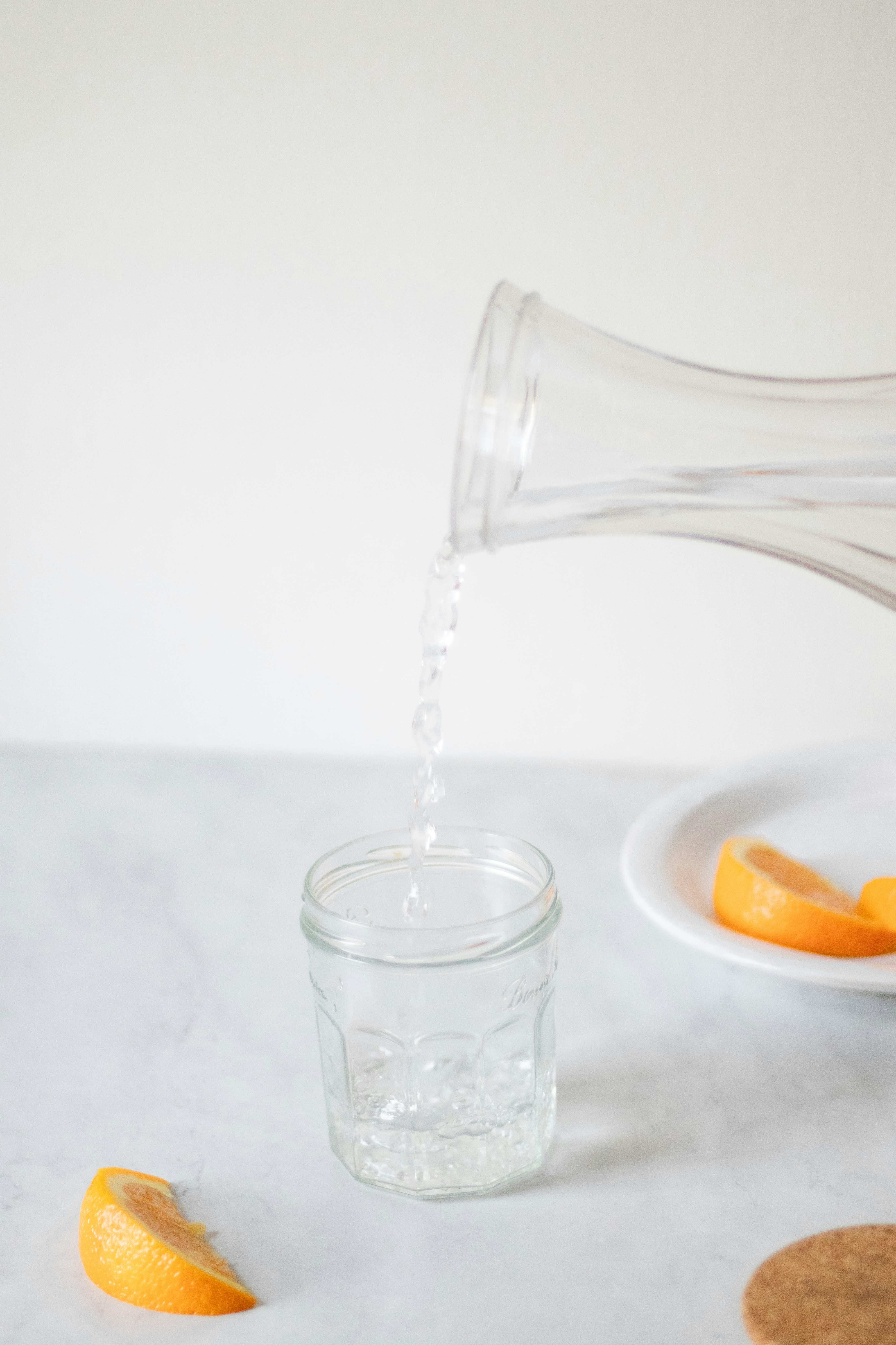 A person pouring water into a glass on a table