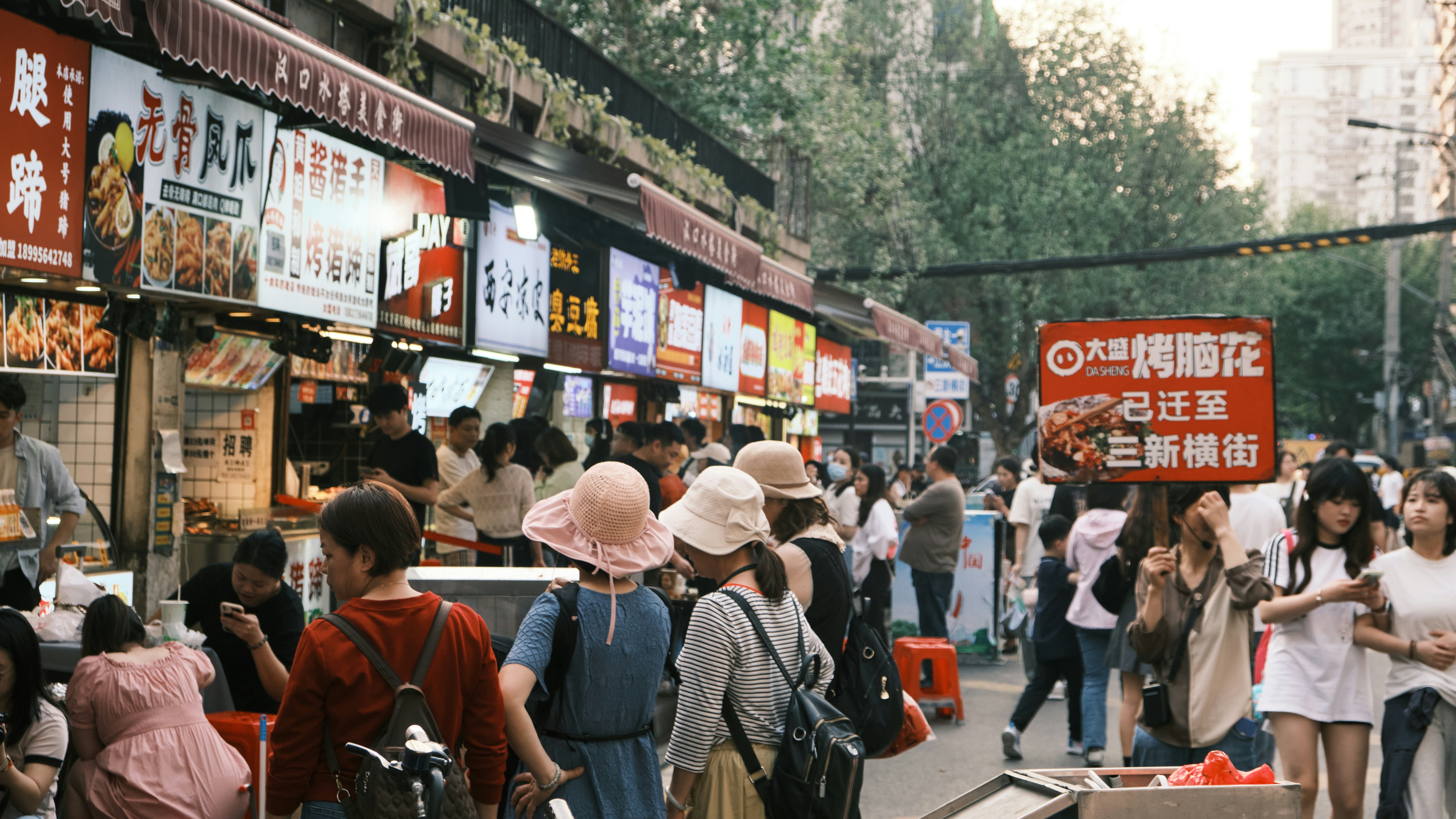 A crowd of people walking down a street next to tall buildings