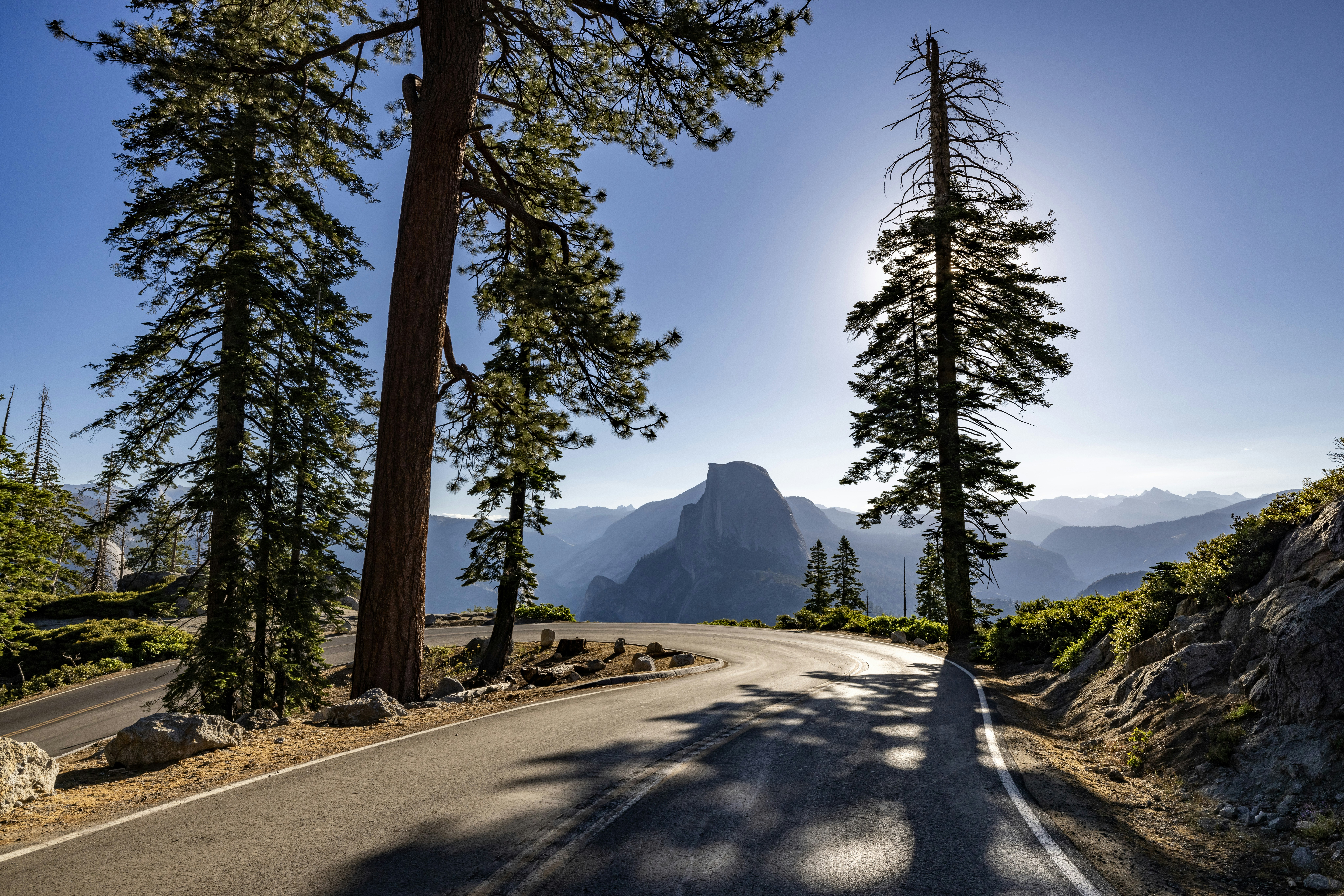 The sun shines brightly on a mountain road