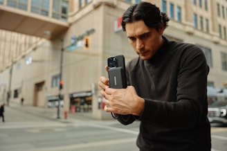A man standing on the street looking at his cell phone