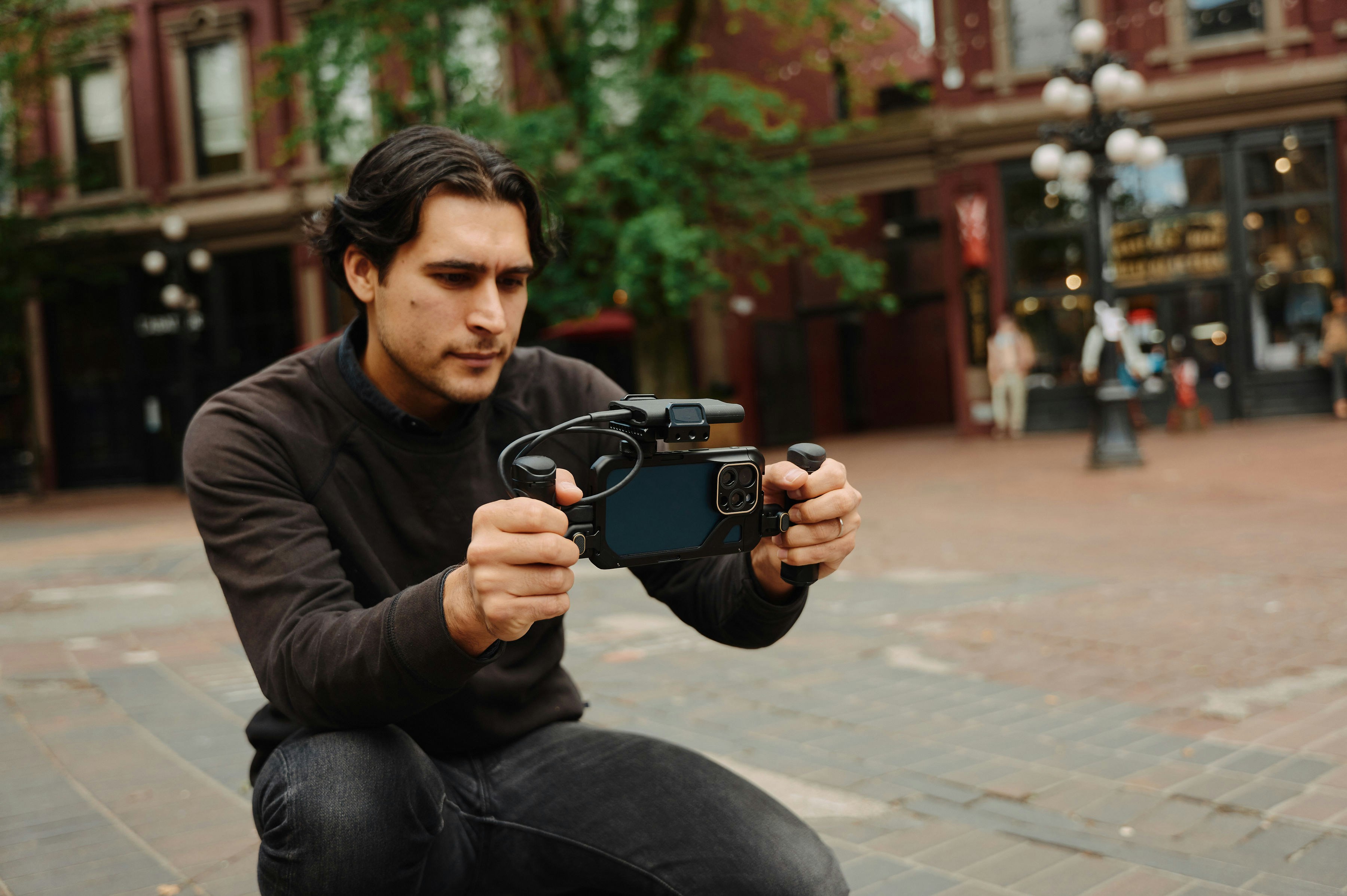 A man kneeling down while holding a camera