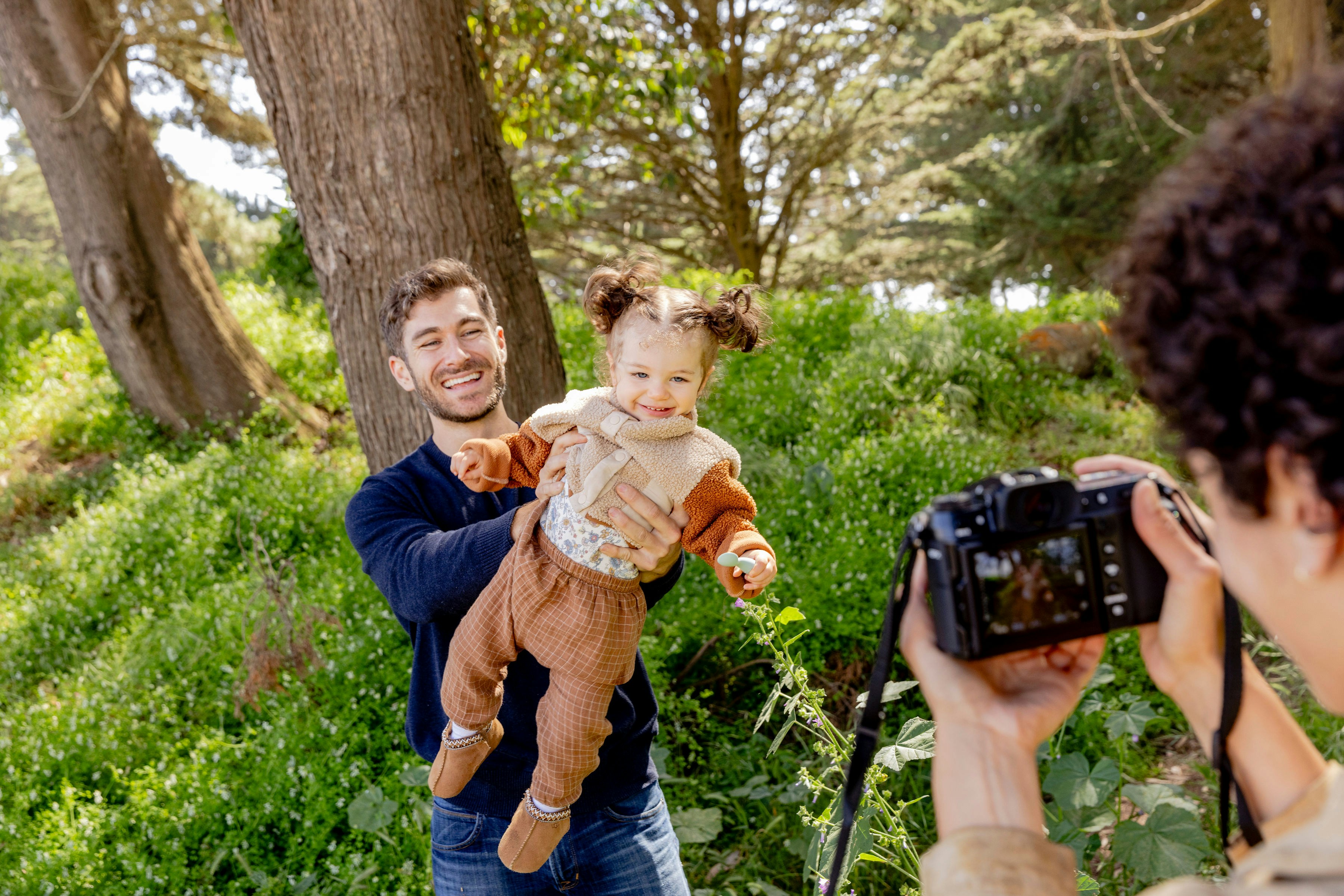 A man taking a picture of a woman holding a baby