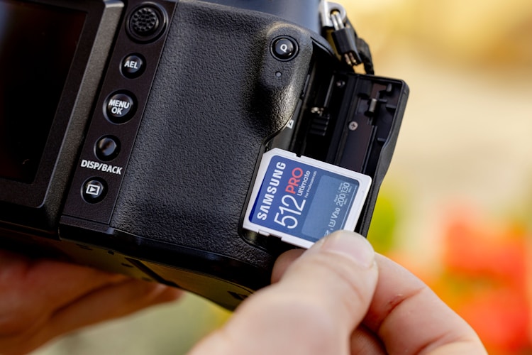 Person holding a camera with a memory card inserted