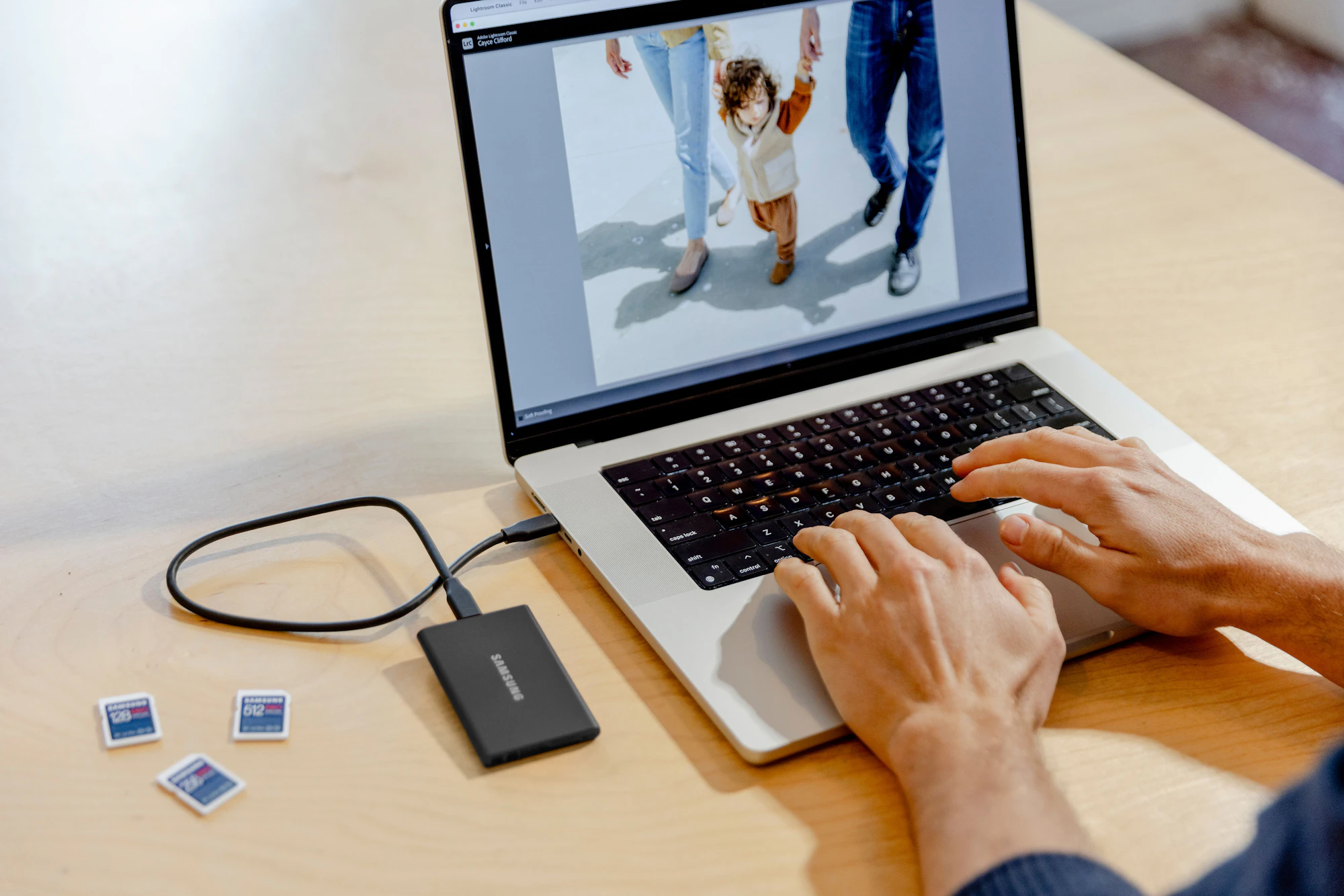 A laptop on a desk connected to a small external hard drive.