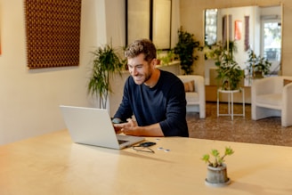 A man sitting at a table using a laptop computer