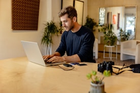 A man sitting at a table using a laptop computer