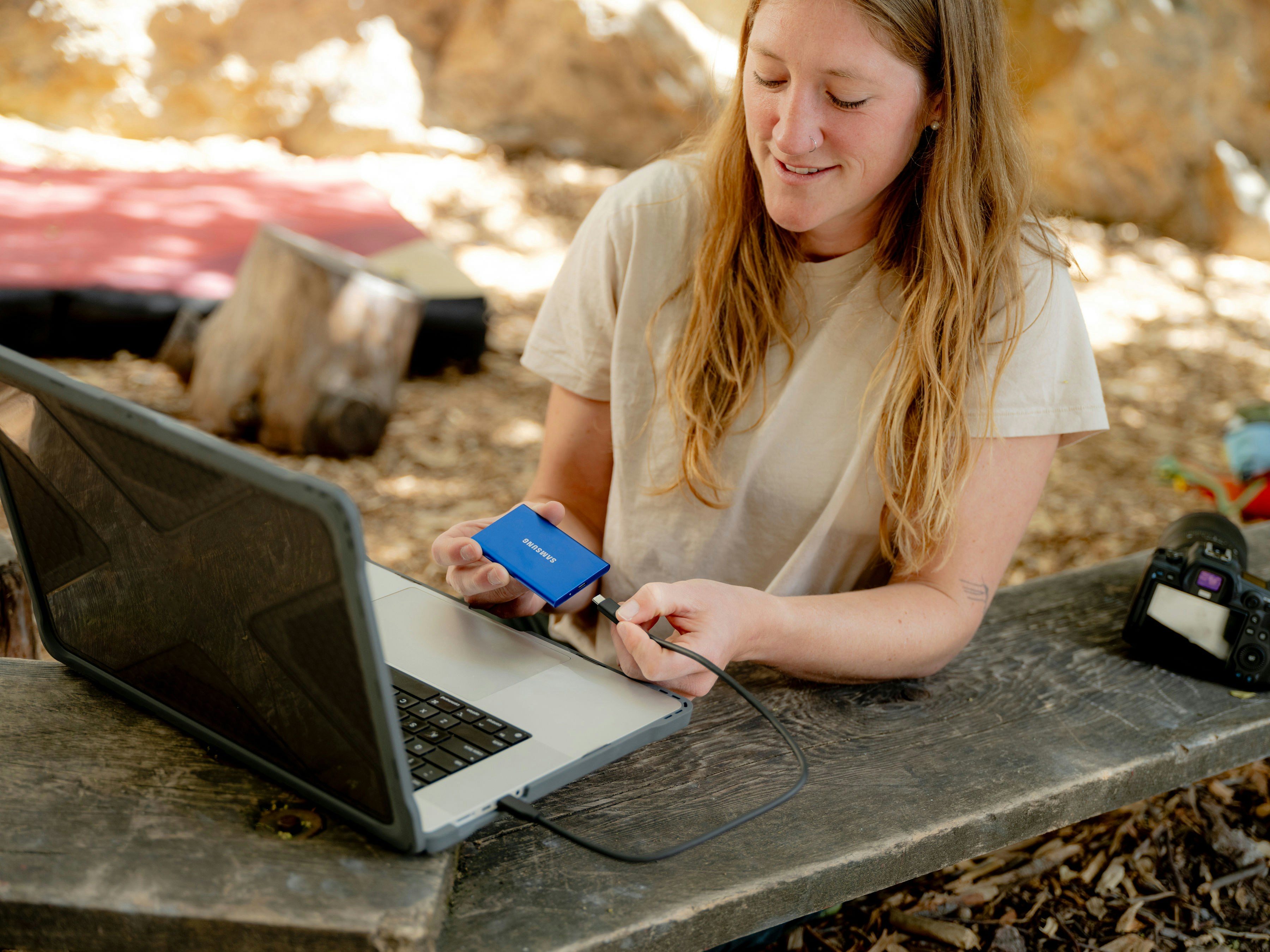 Technical specs of rugged laptops for civil engineering - a student sitting on a rocky outdoor terrain, surrounded by surveying equipment, with a rugged laptop open on their lap, capturing data in the field