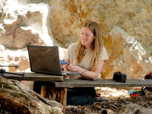 A woman sitting at a picnic table using a laptop computer