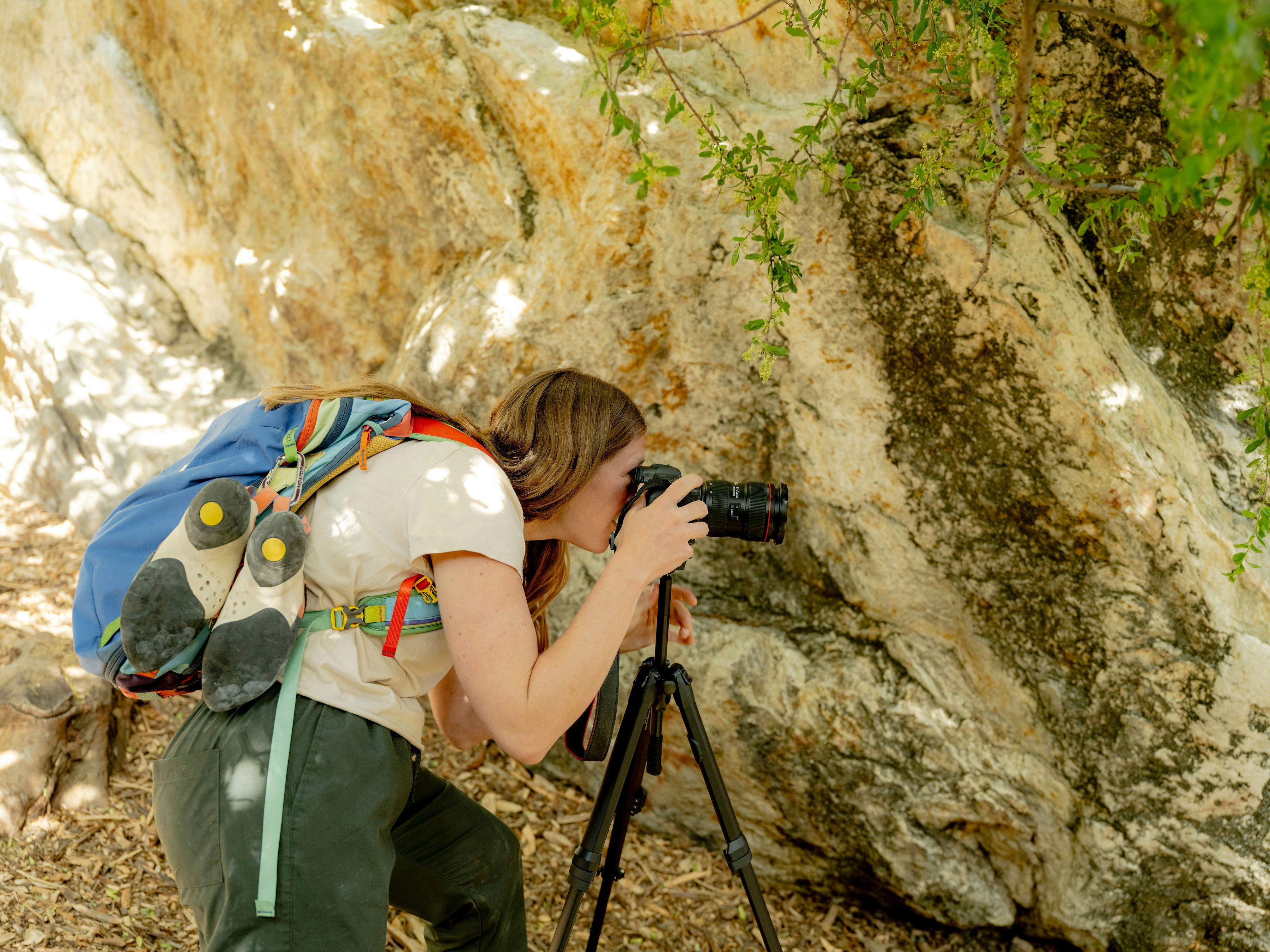 A woman taking a picture of a rock with a camera