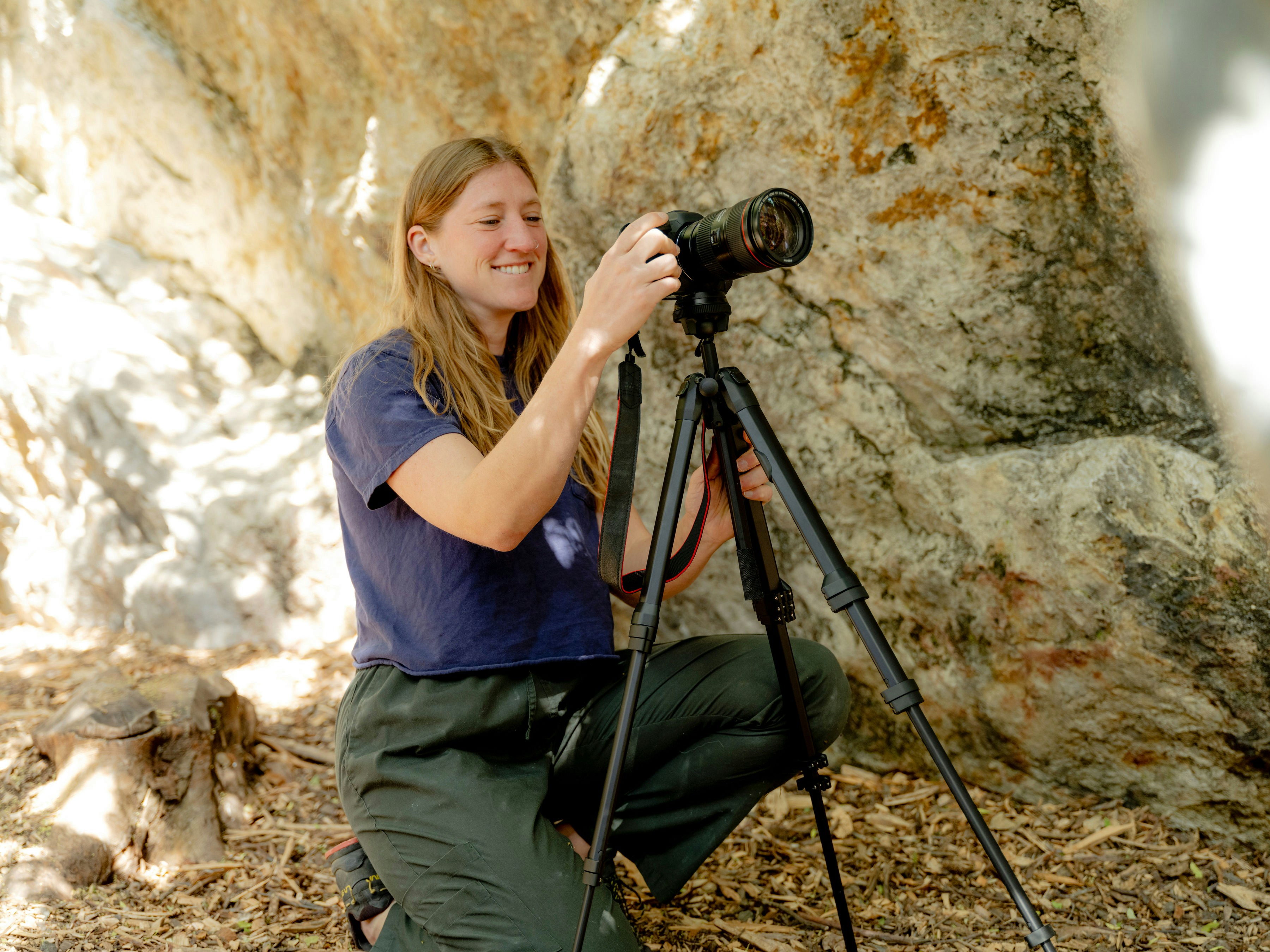 A woman kneeling down with a camera on a tripod