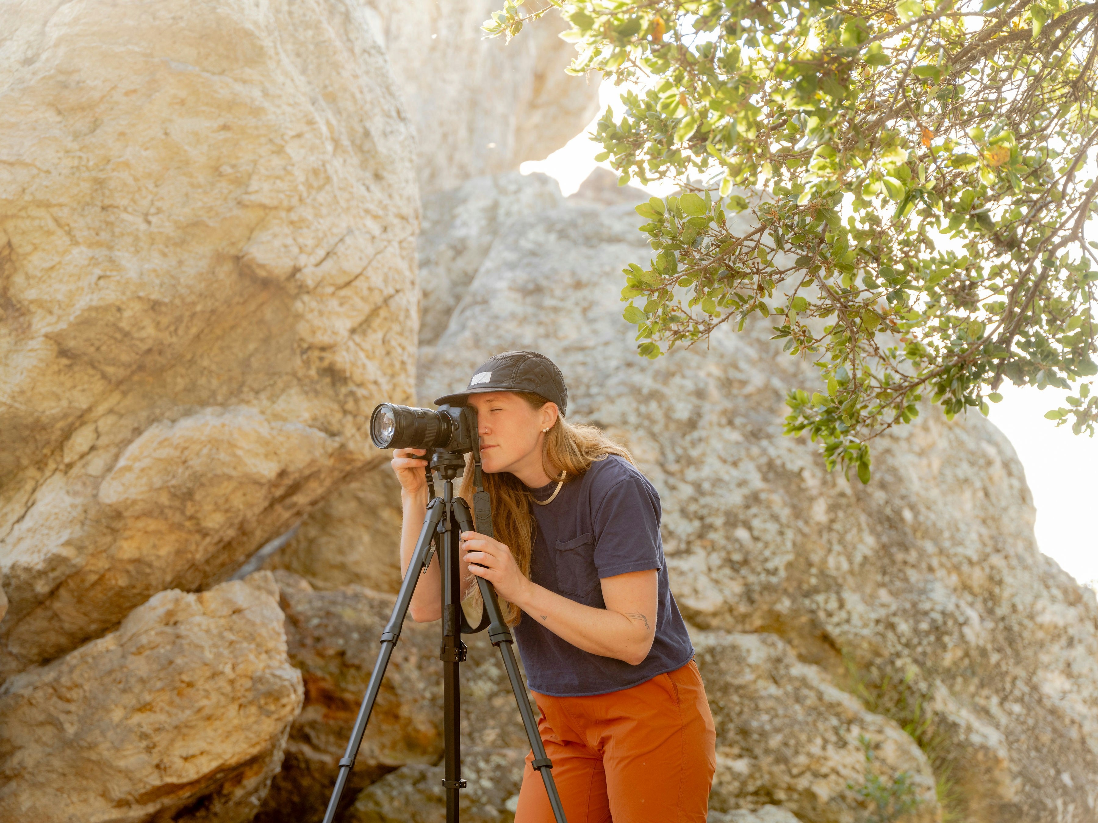 A woman taking a picture of a rock with a camera