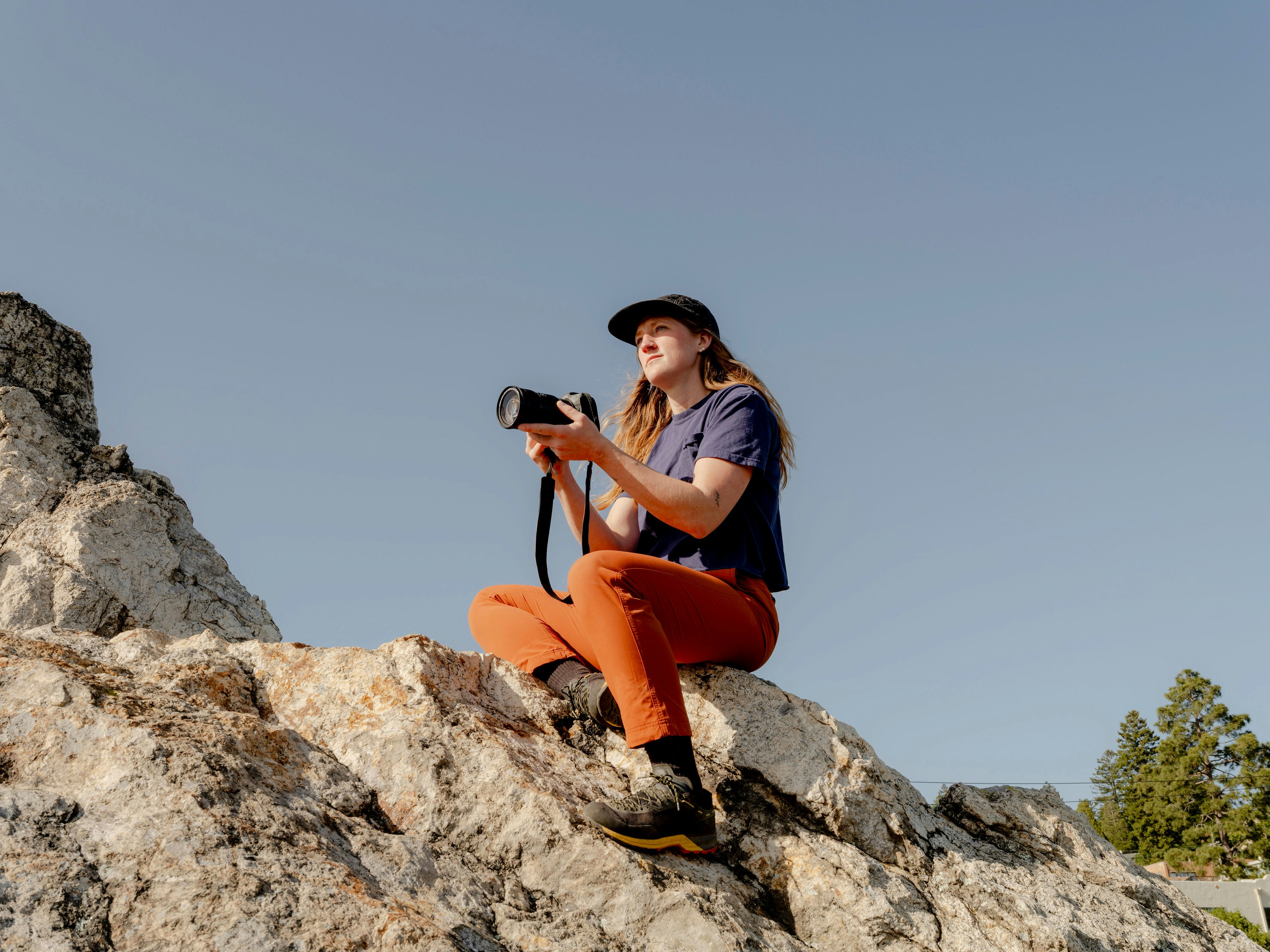 A man sitting on top of a rock holding a camera