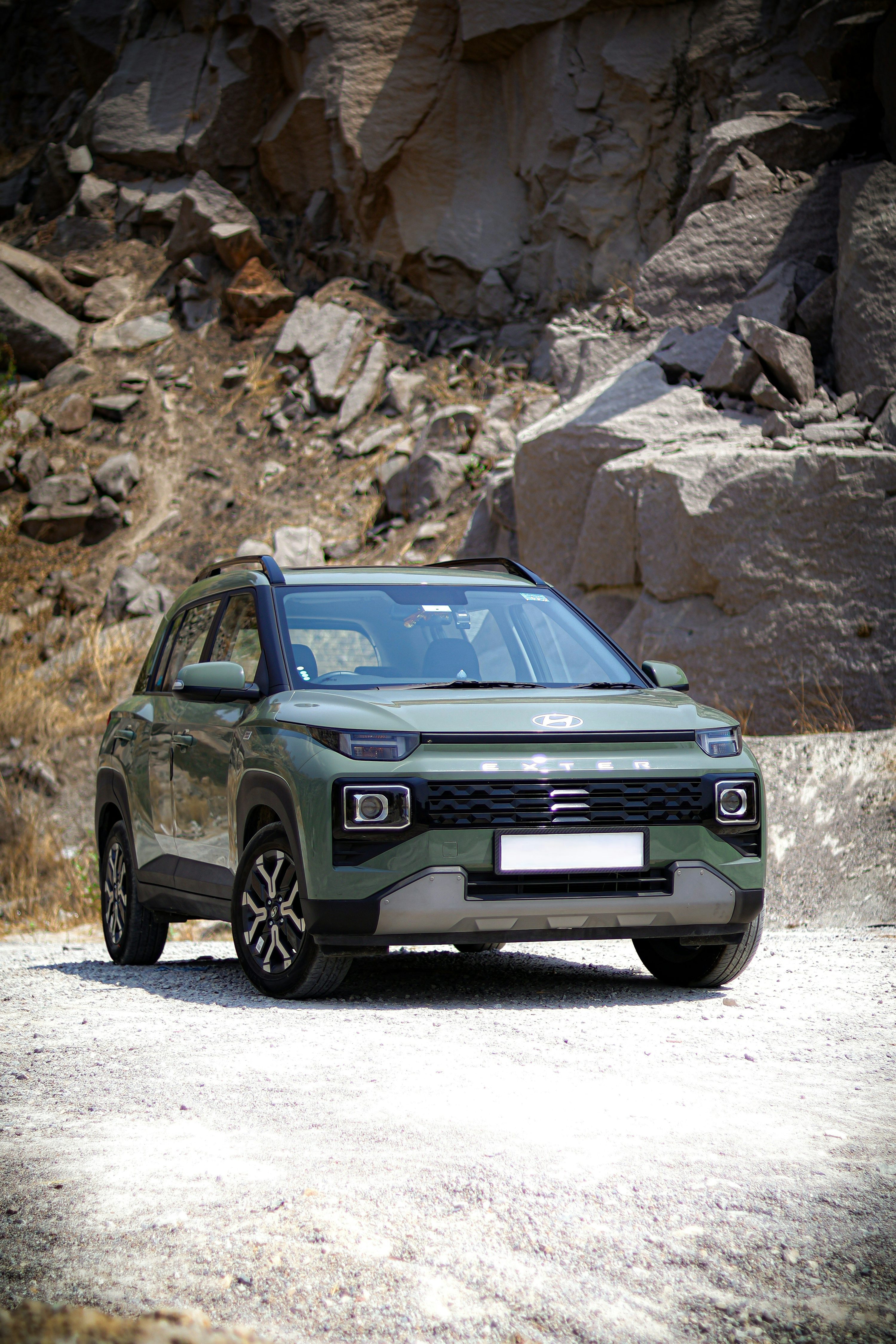 A green car driving down a dirt road