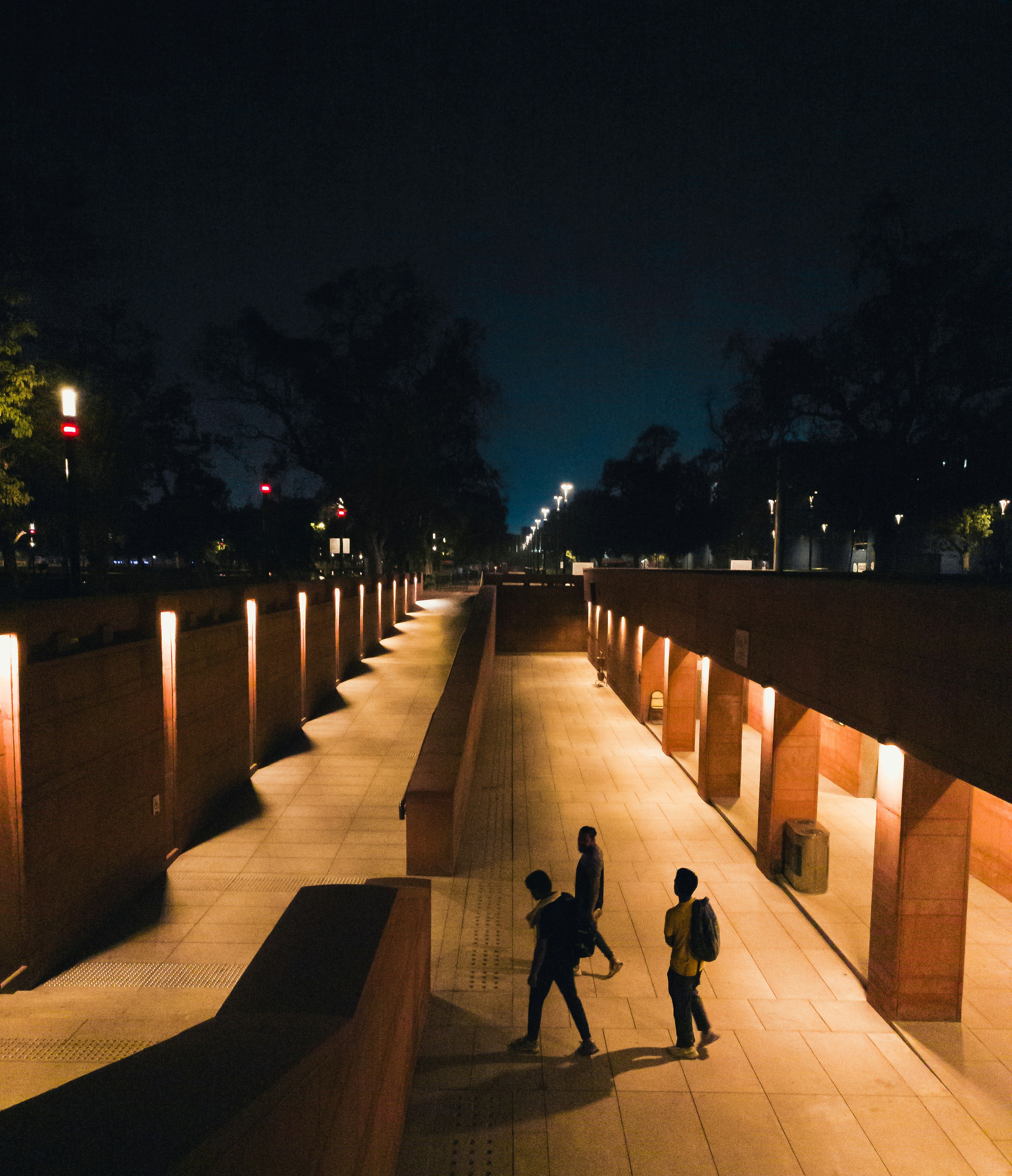 A couple of people walking down a walkway at night