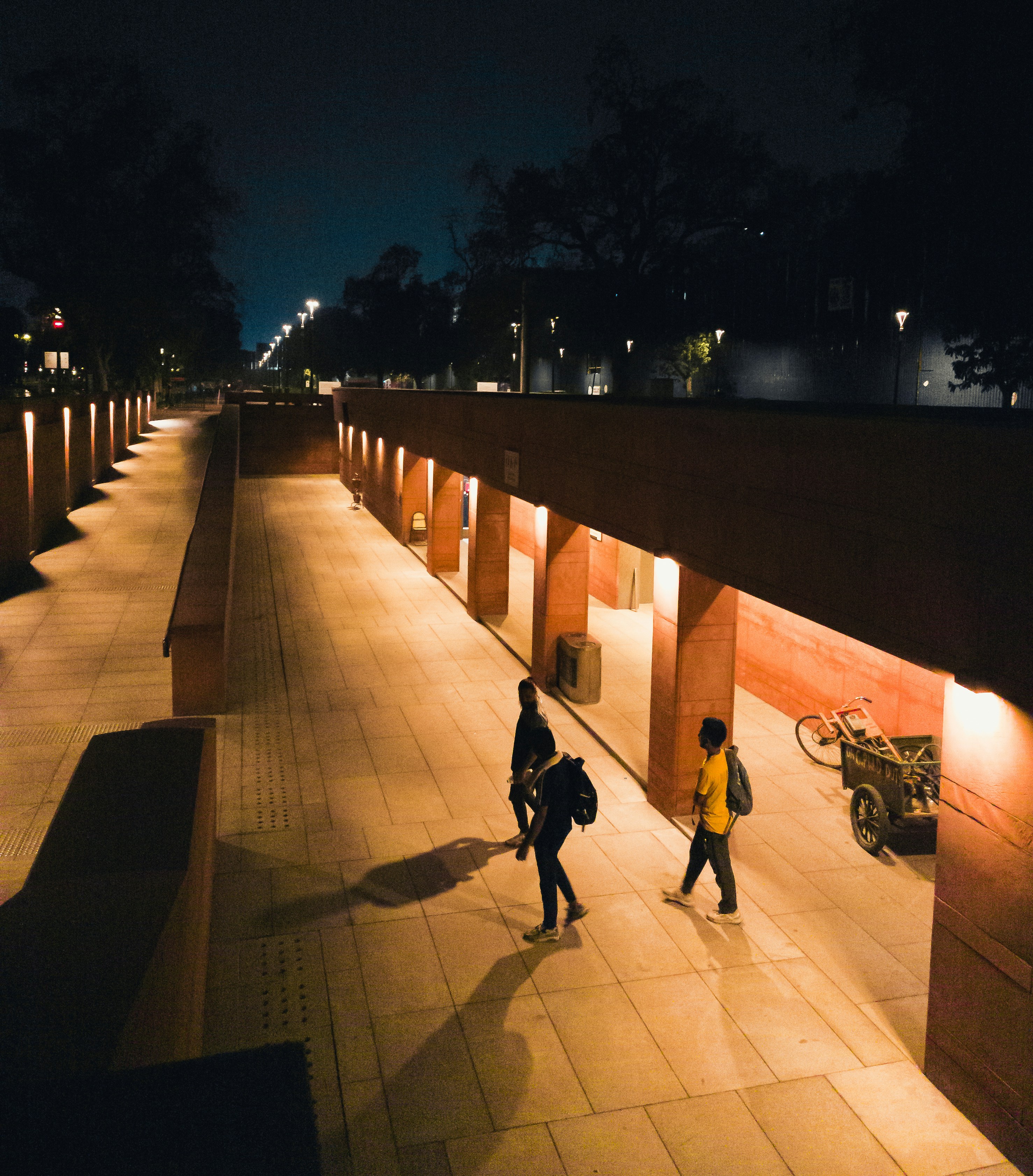 Two people walking down a walkway at night