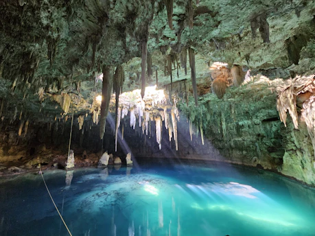 A blue pool in a cave with icicles hanging from the trees