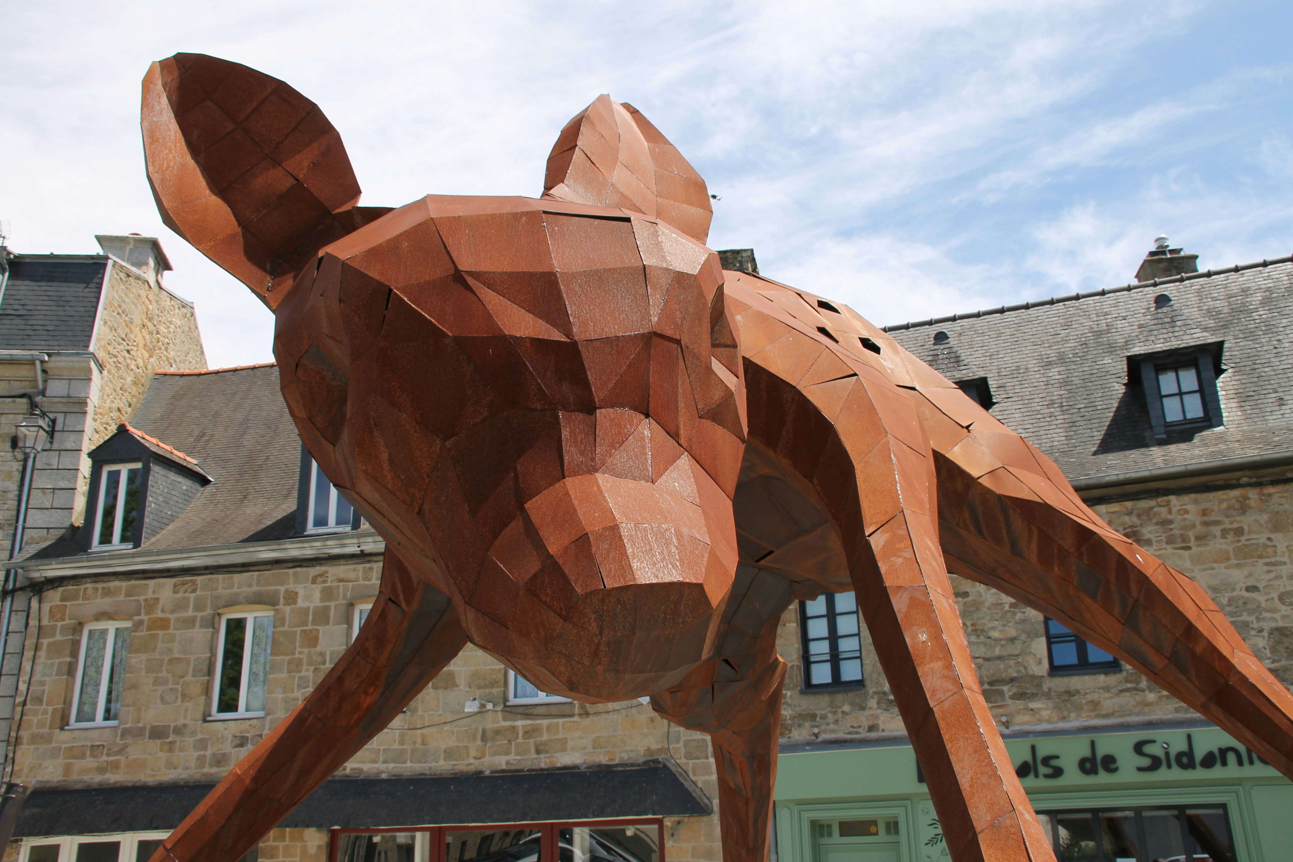 Une statue de chien en bois devant un immeuble