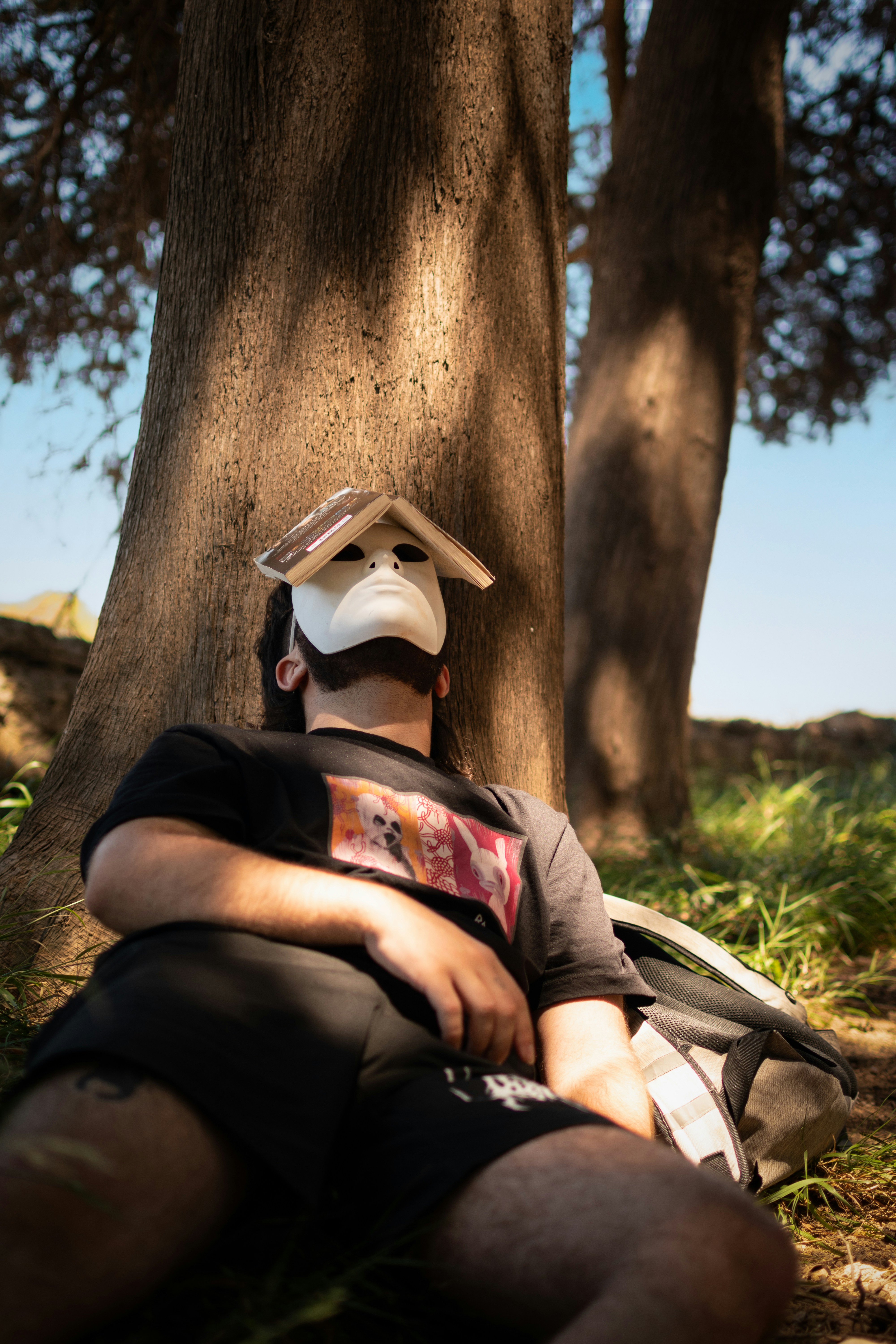 Ein Mann, der mit einem Hut auf dem Kopf unter einem Baum sitzt