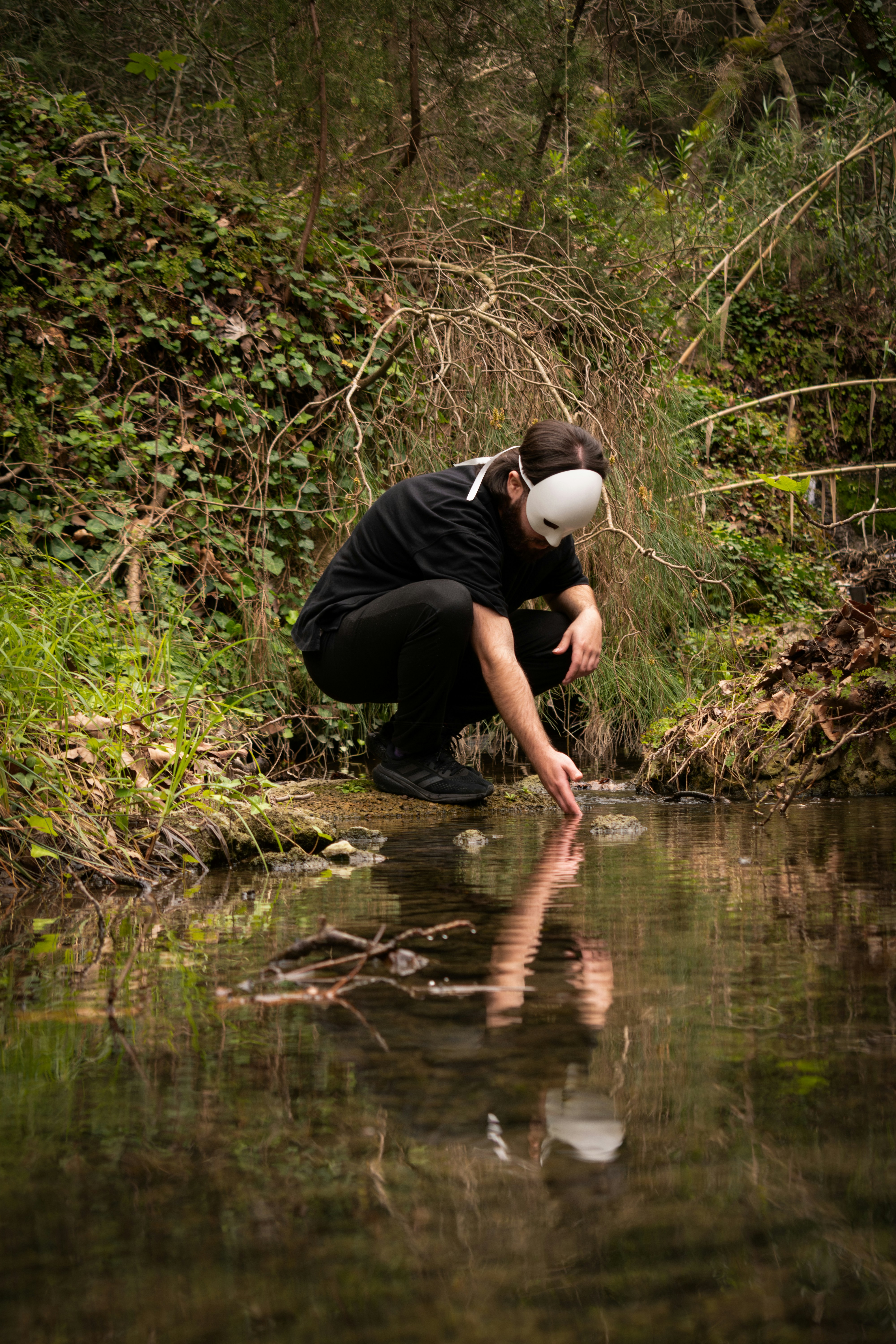 Ein Mann geht in die Hocke und schaut auf das Wasser