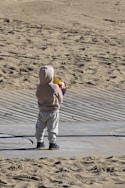 A small child standing on top of a sandy beach