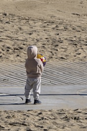 A small child standing on top of a sandy beach