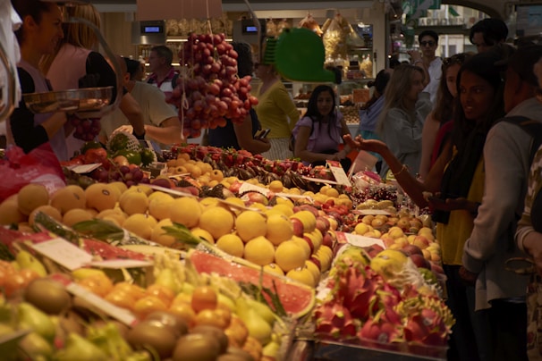 A group of people standing around a fruit stand