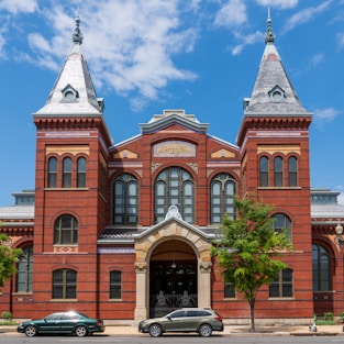 Two cars are parked in front of a large building