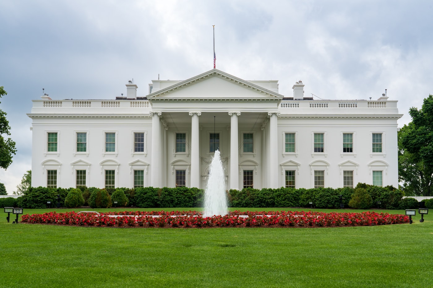 A close-up photo of a hand holding a fountain pen above a signed executive order document.
