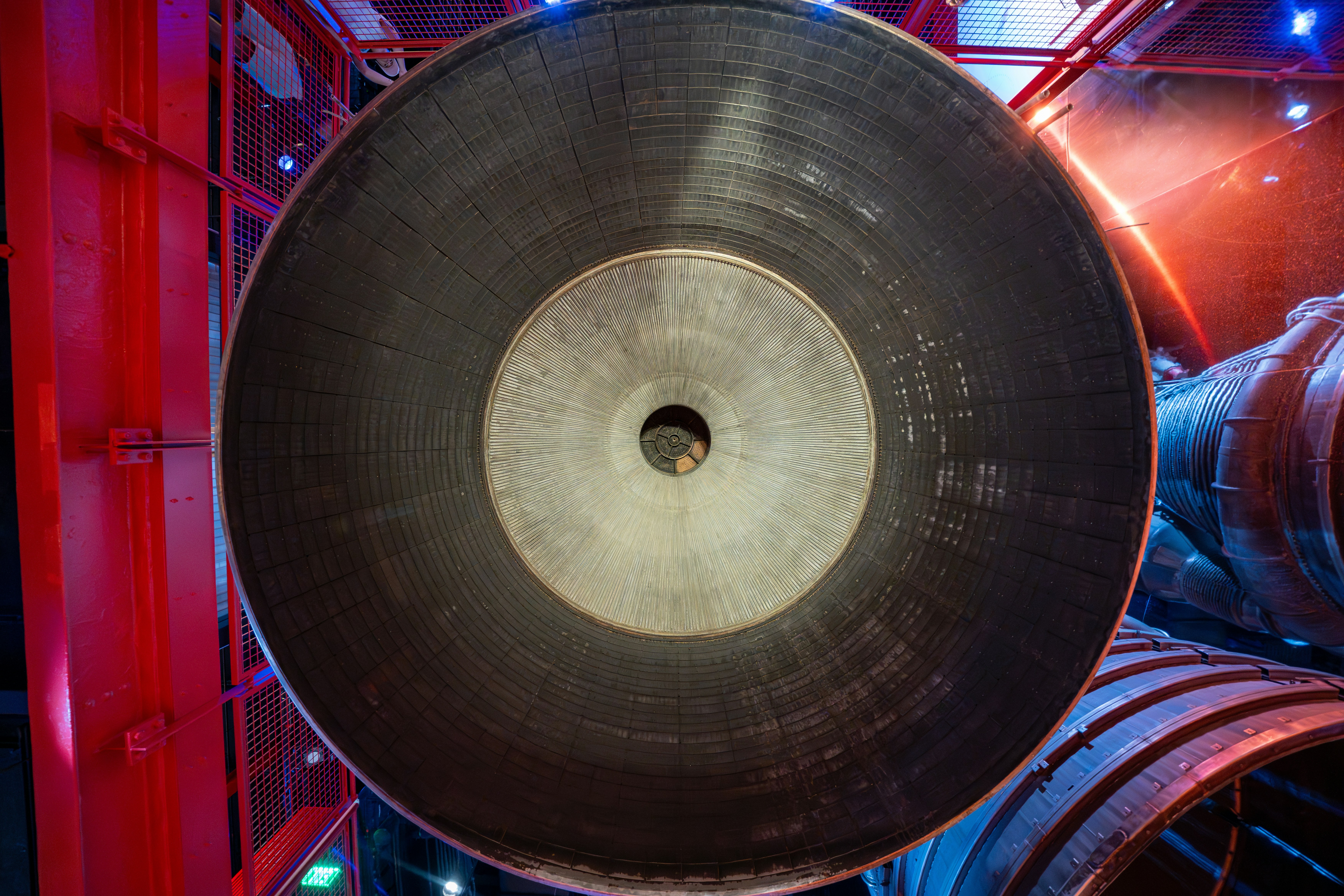 Rocket engine nozzle close-up, dark industrial setting, orange heat glow, dramatic shadow contrast