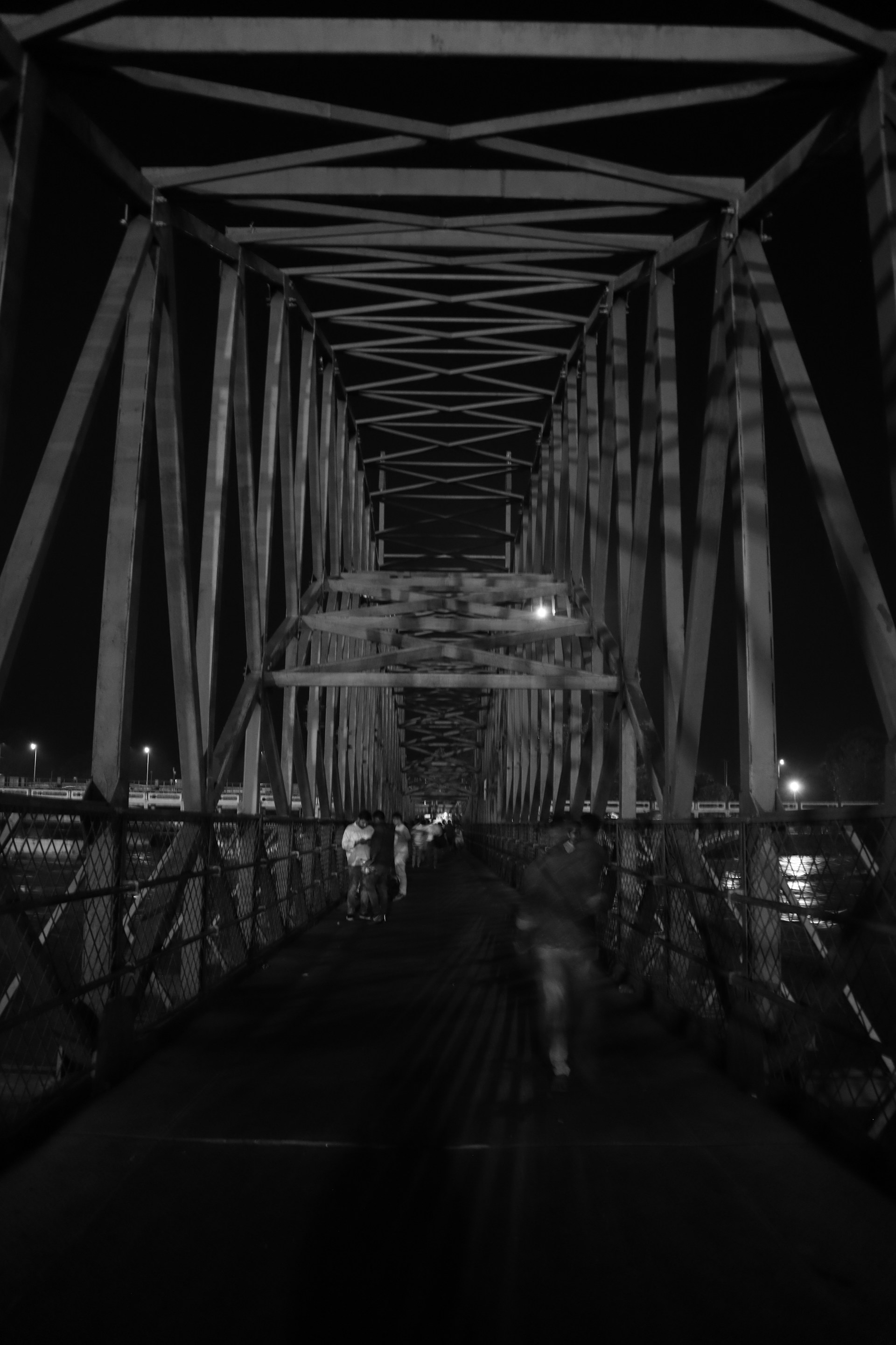 A black and white photo of people walking across a bridge