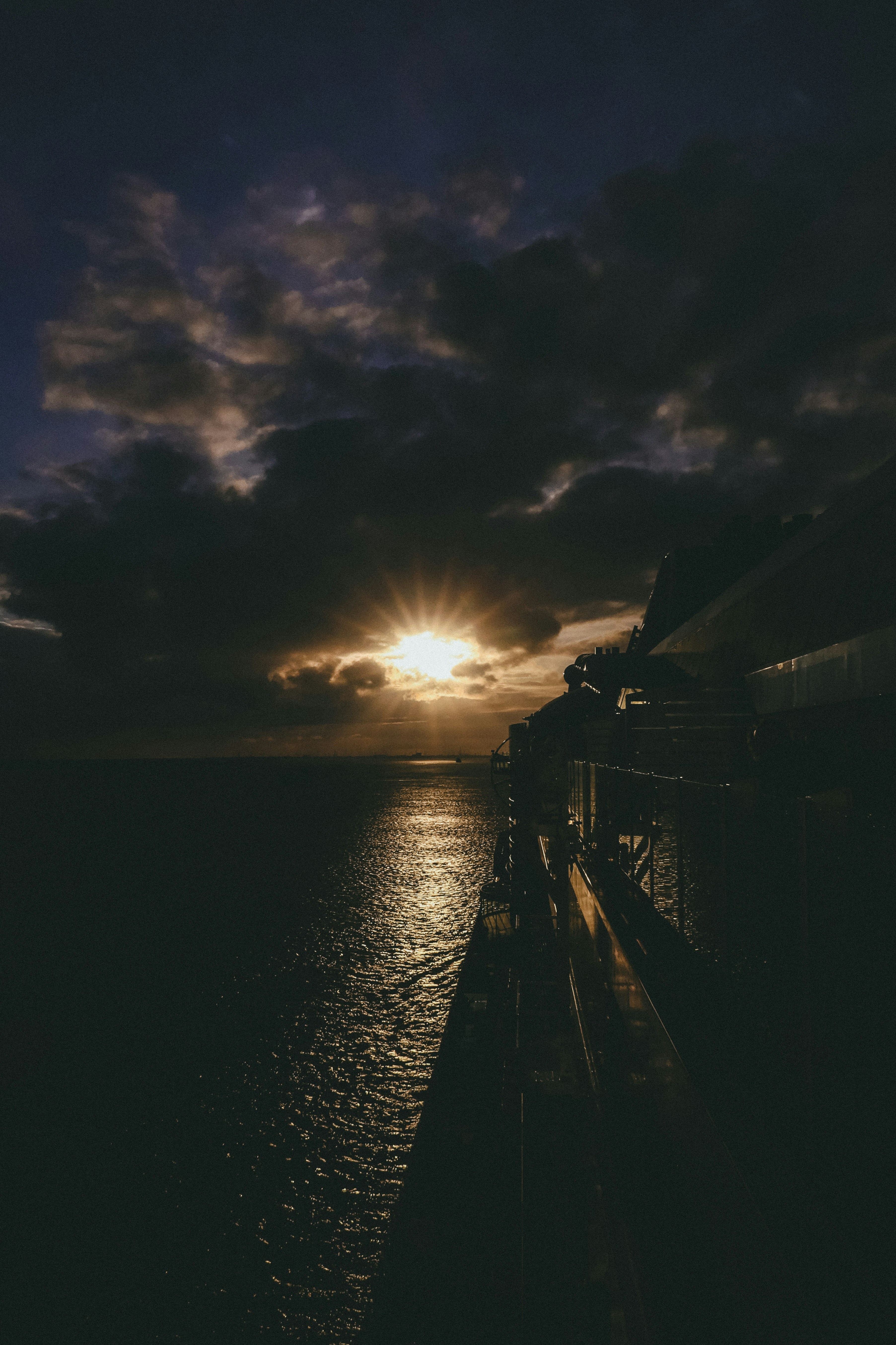 The sun is setting over the ocean on a cloudy day