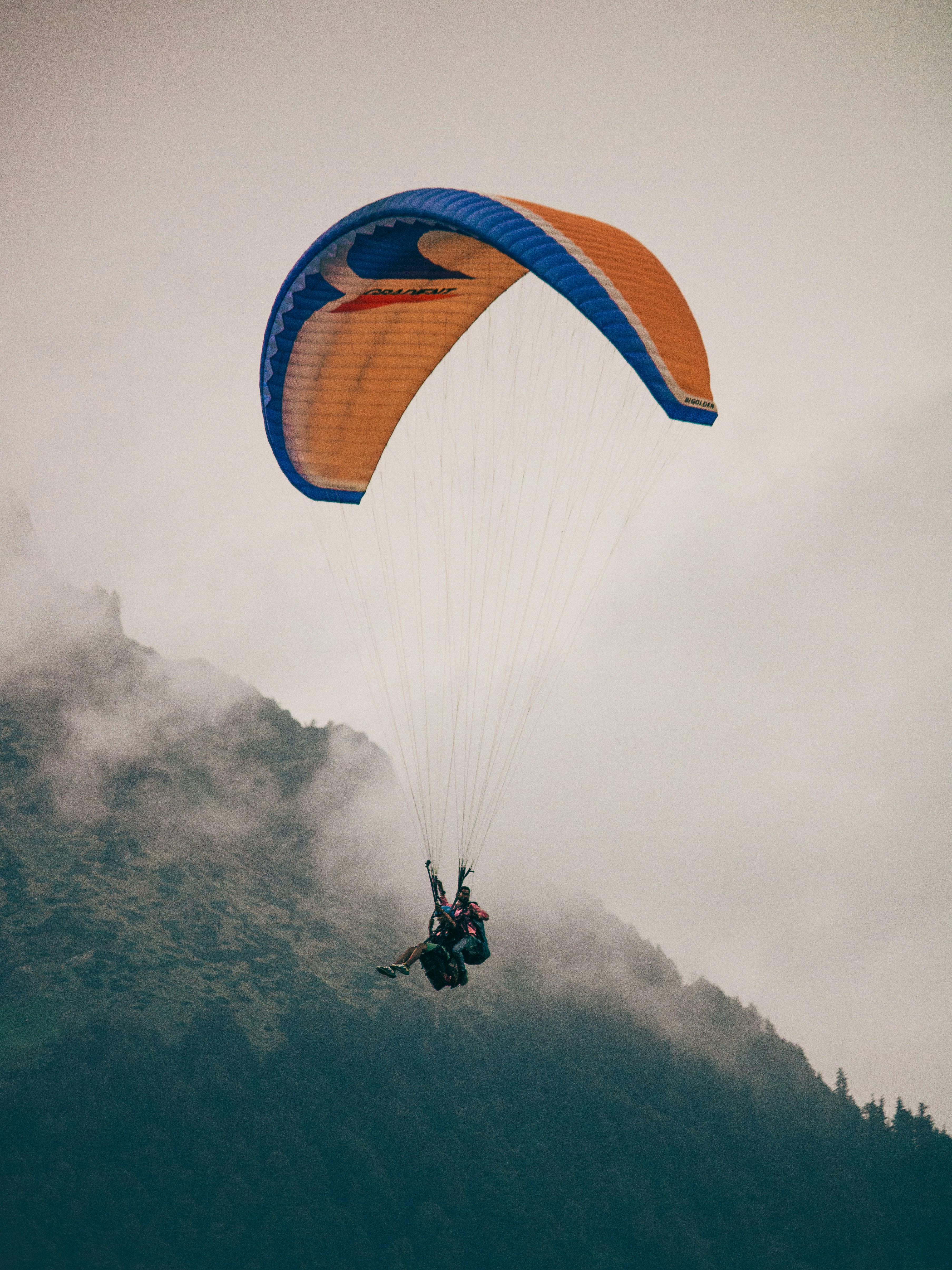 A person is parasailing in the air over a mountain