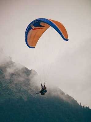 A person is parasailing in the air over a mountain