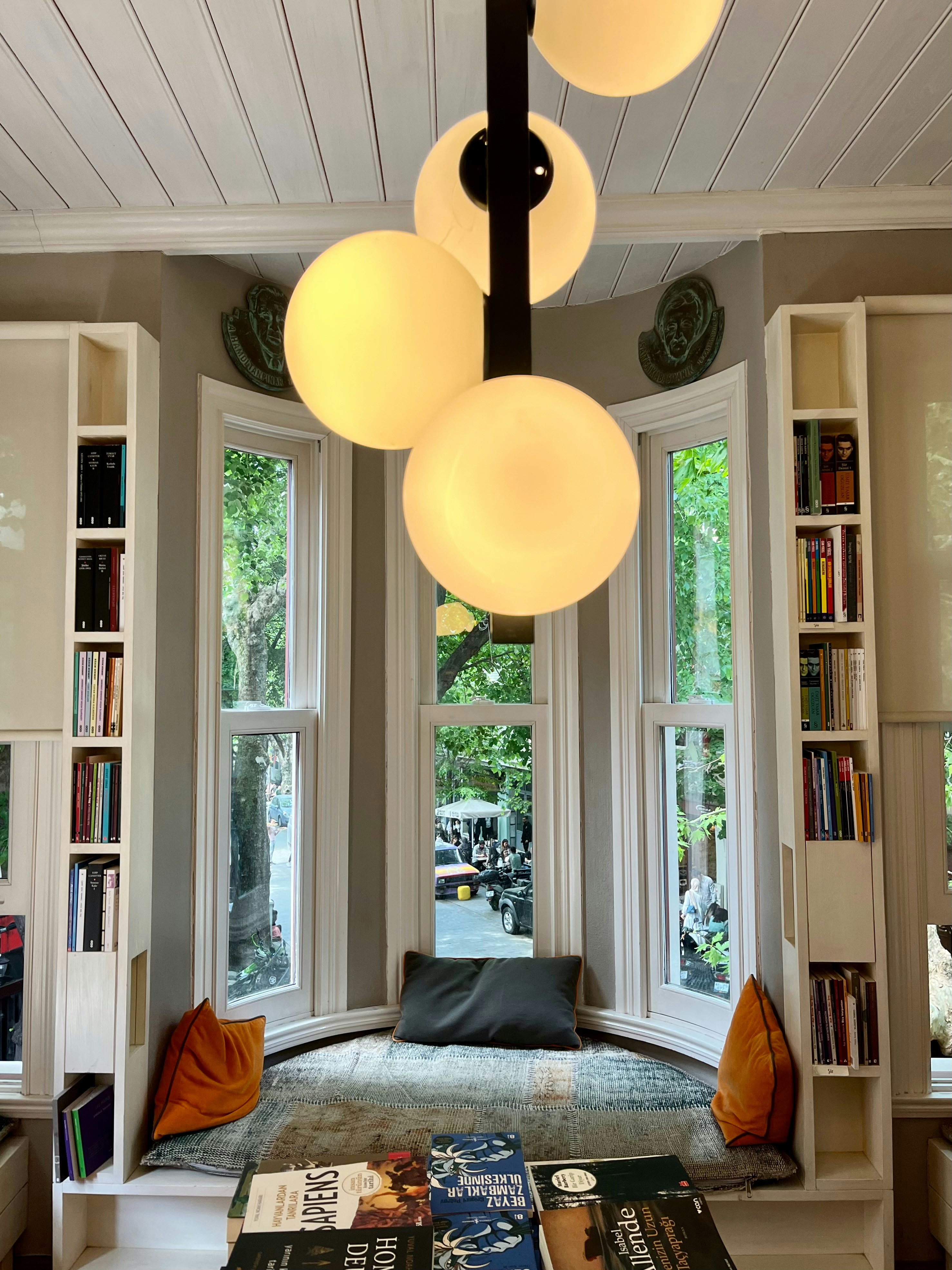 Cozy window seat with soft cushions overlooking a tree-lined street
