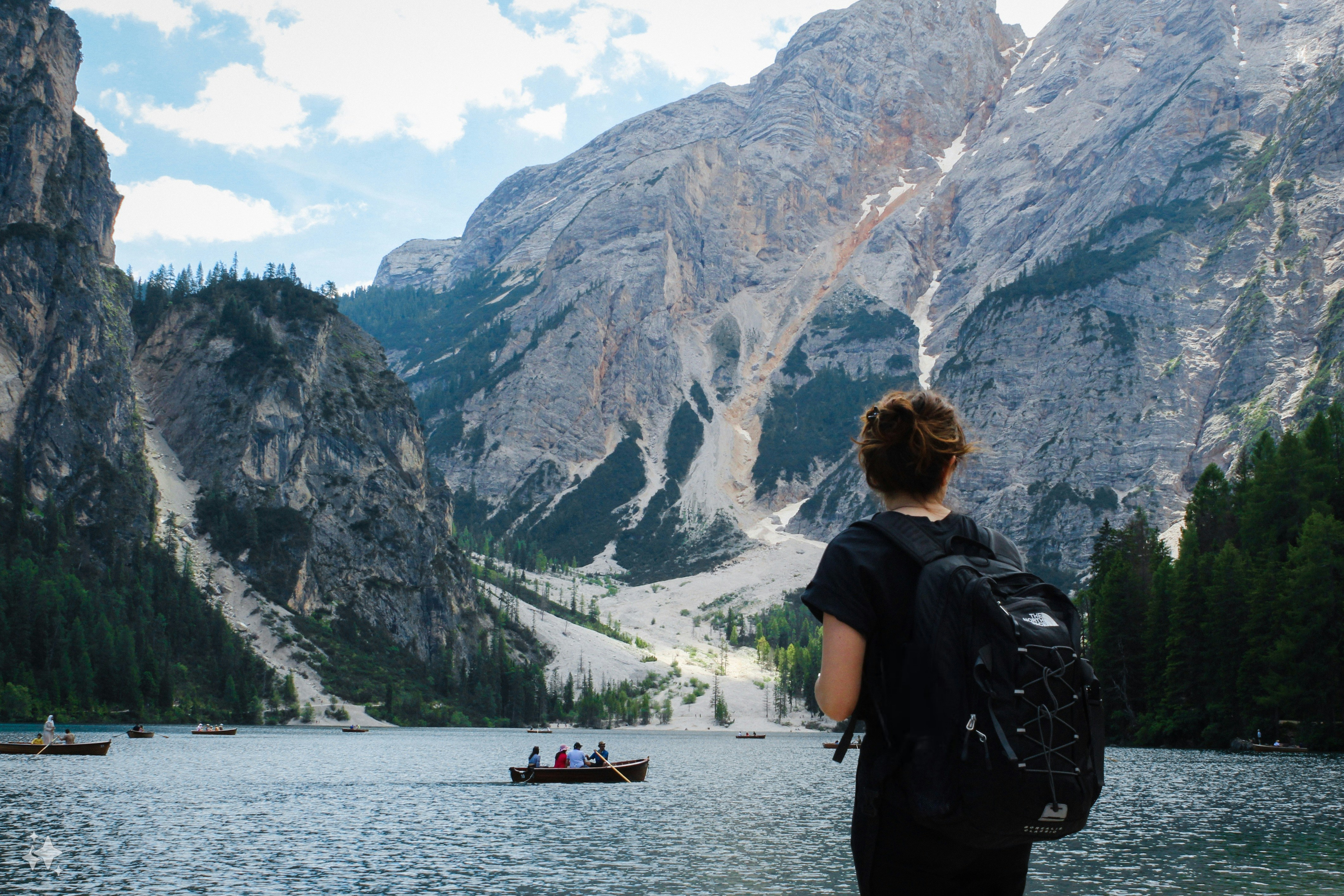 A person with a backpack looking at a mountain lake